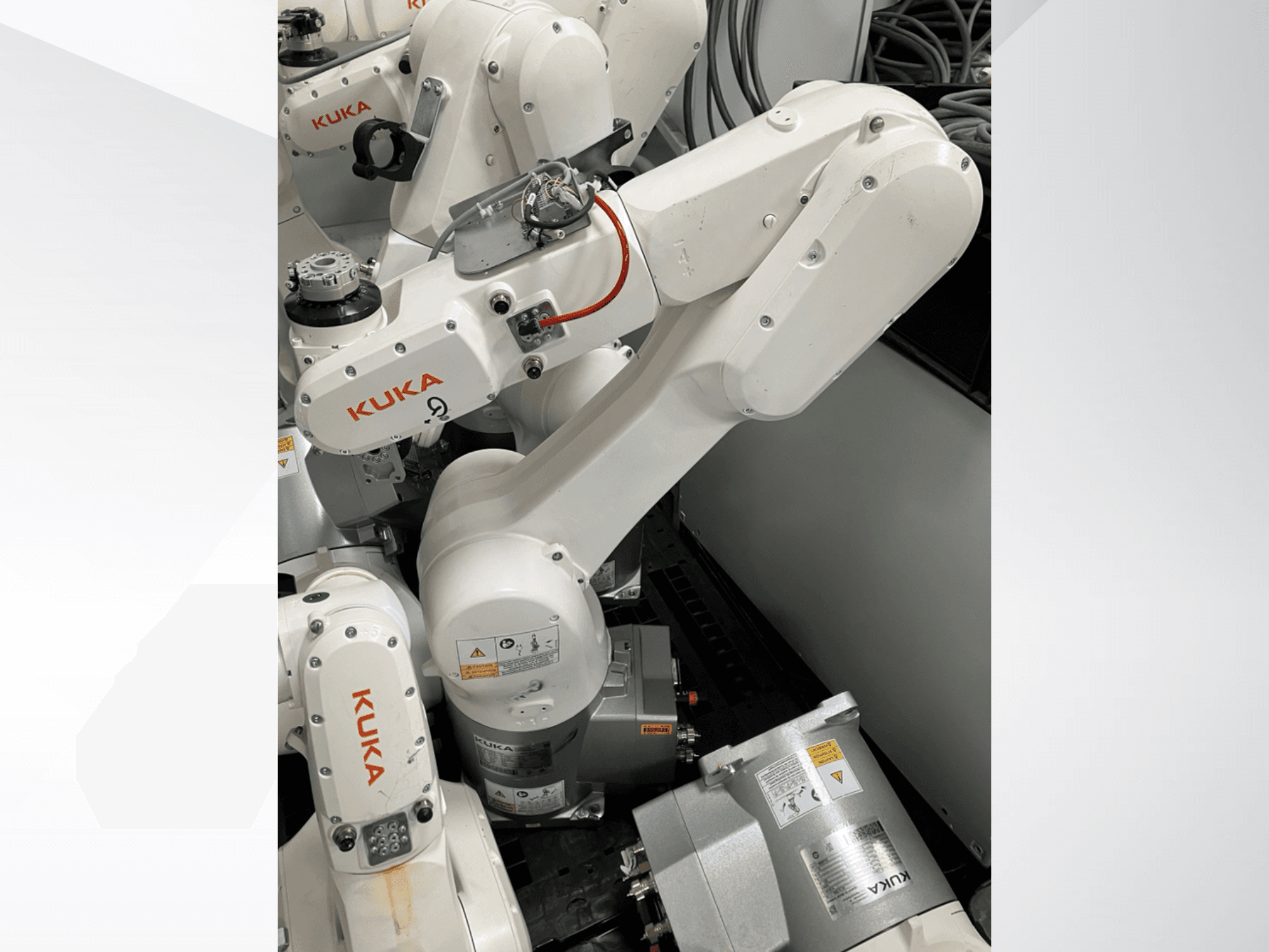 Brazo robótico KUKA KR 6 R900 CR, vista lateral; presenta motores y conectores visibles, advertencias de seguridad etiquetadas y brazos mecánicos.