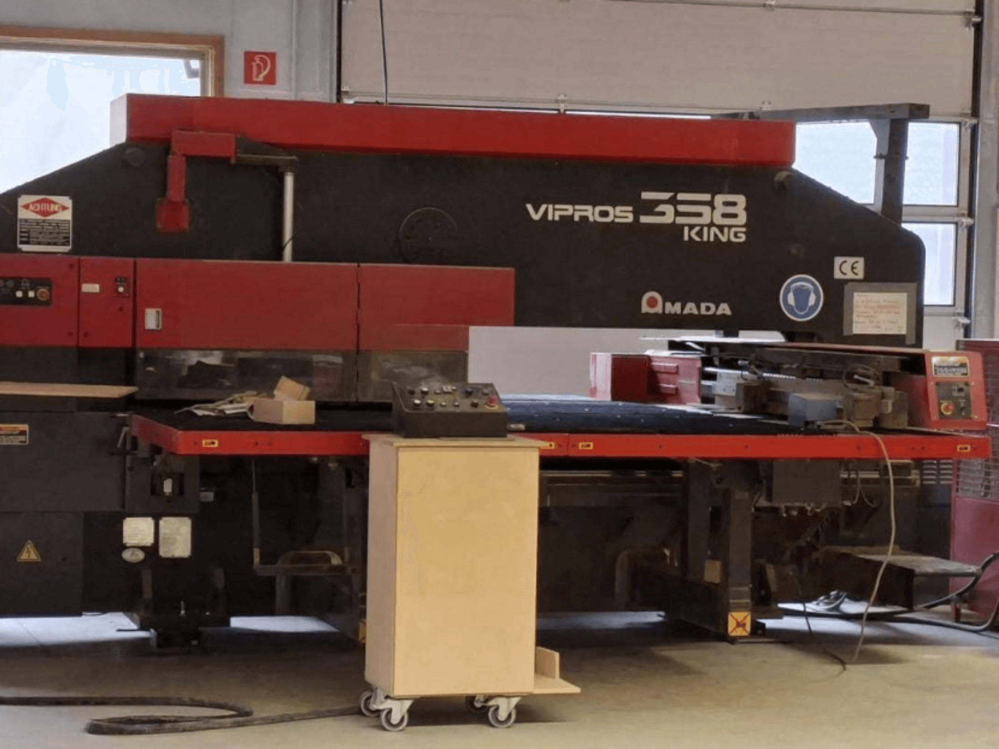 Prensa punzonadora CNC AMADA VIPROS 358 KING vista de perfil, en la que se aprecian el panel de control y la zona de almacenamiento de herramientas.