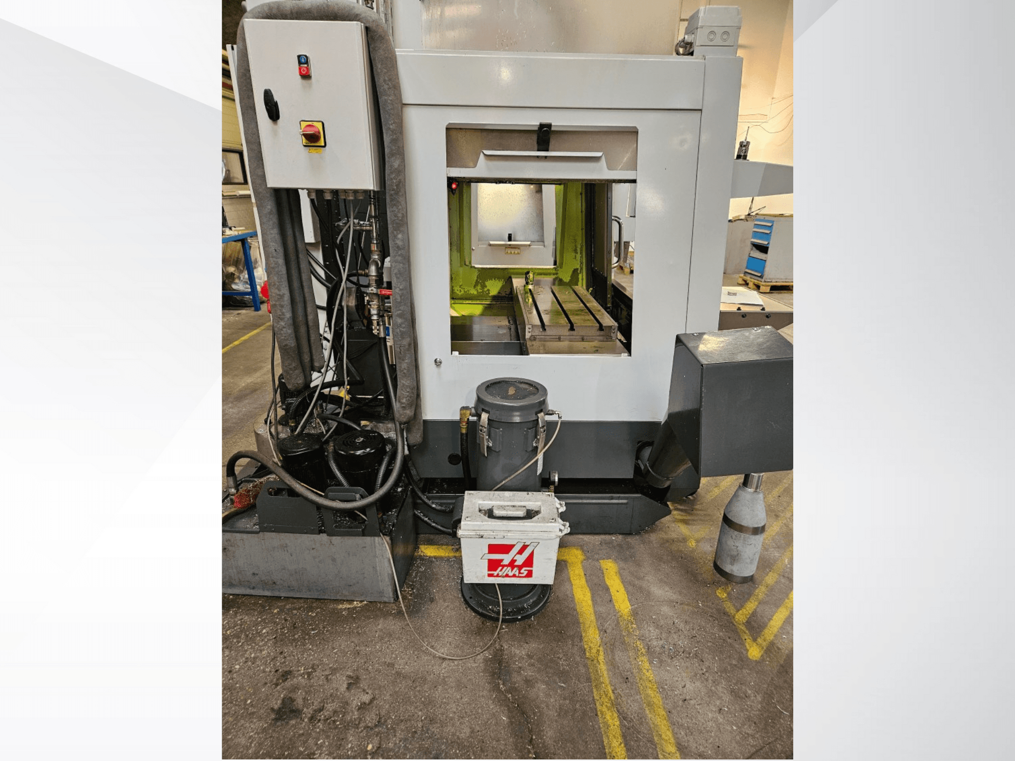 Vista frontal de la máquina CNC Haas que muestra el panel de control, el depósito de refrigerante y la bancada mecanizada.