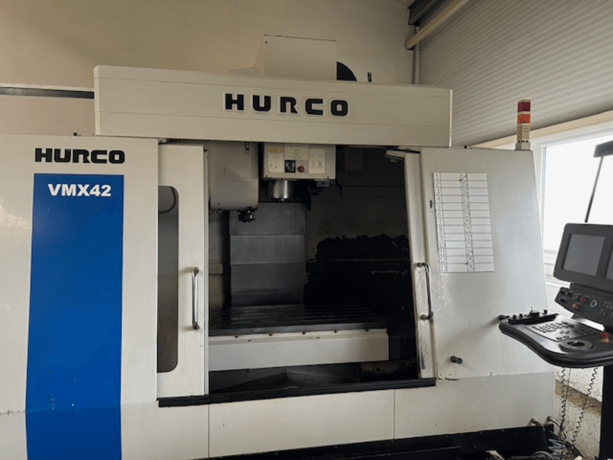 Máquina CNC Hurco VMX42 en vista frontal, mostrando el panel de control, el husillo y el área de trabajo; revelando la disposición operativa.
