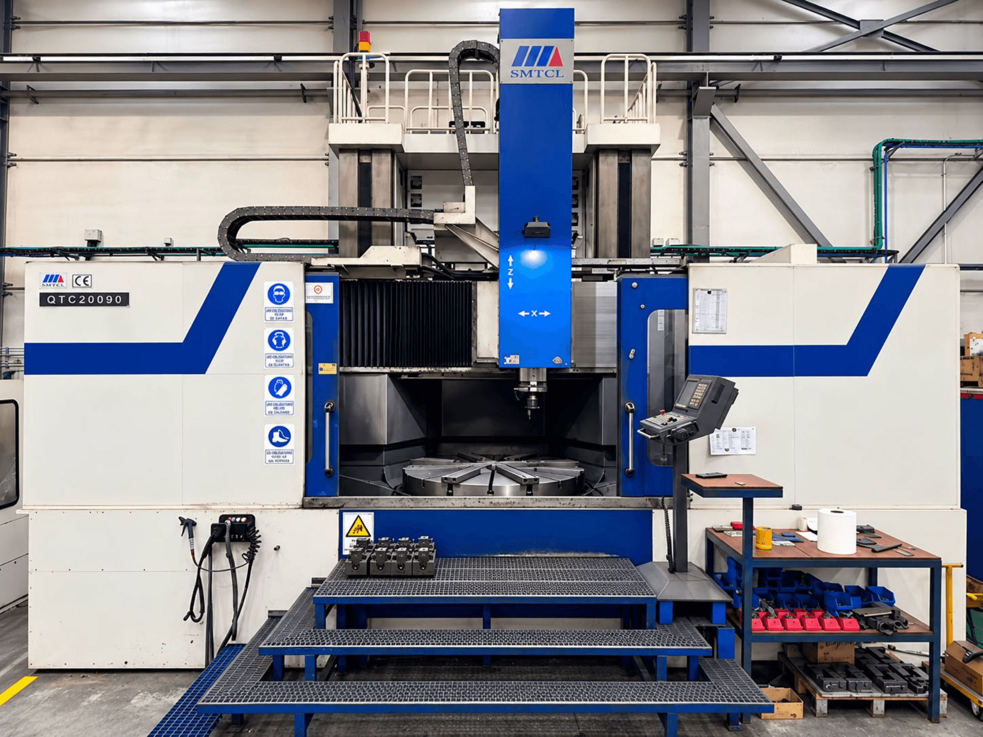 Torno vertical SMTCL QTC 20090 en un taller, vista frontal, en la que se aprecian el panel de control y la mesa de trabajo.