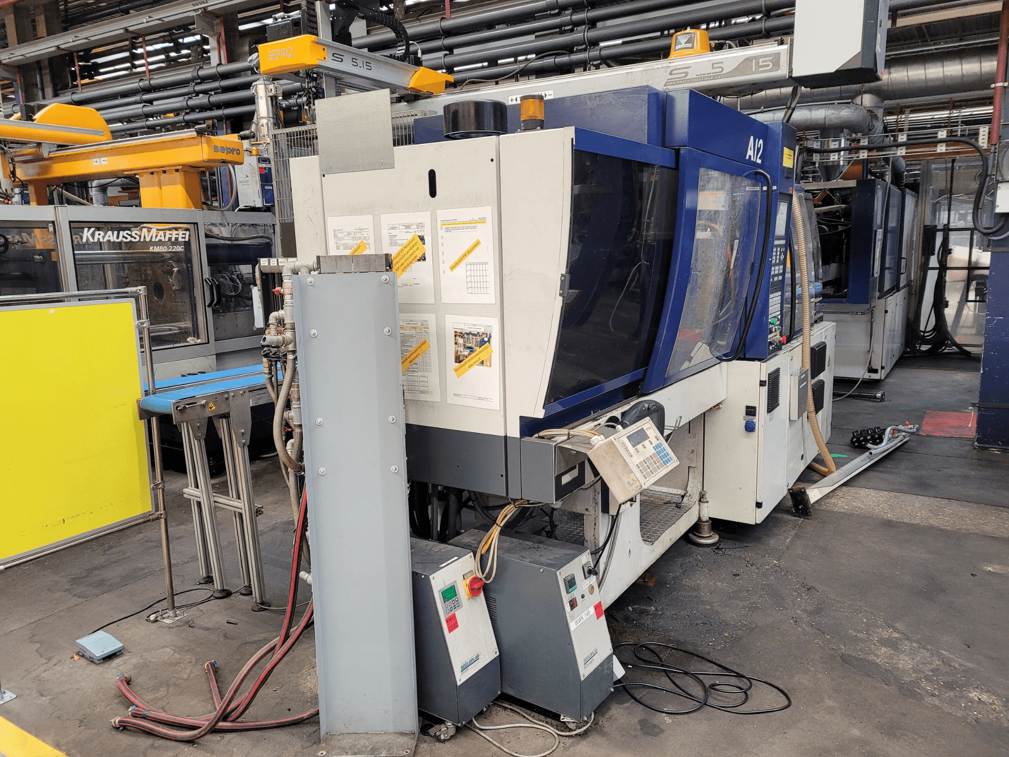 Máquina de moldeo por inyección KraussMaffei modelo KM80-232G, vista frontal, con panel de control y componentes operativos.