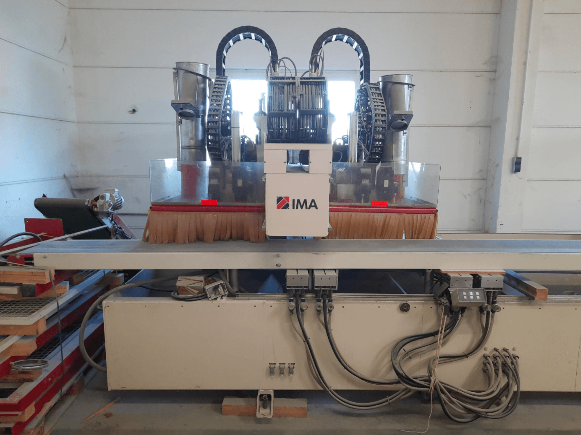 Centro de mecanizado de madera CNC IMA BIMA 610 V visto desde delante, en el que se aprecian los cepillos, los mandos y la mesa de trabajo.