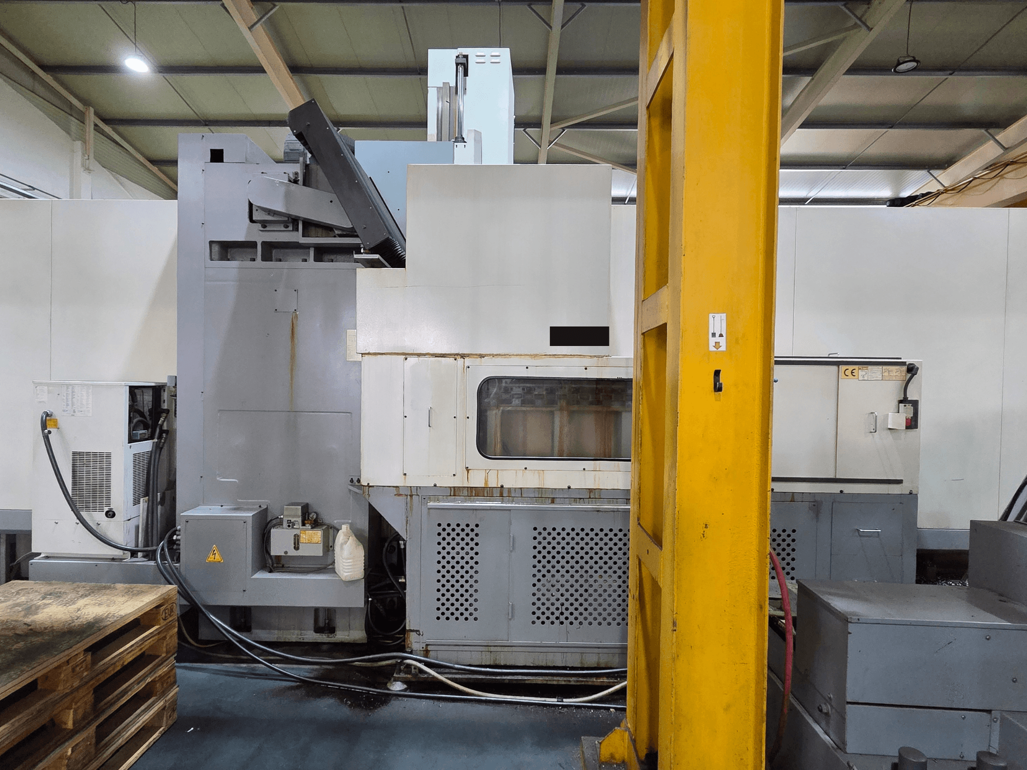 Centro de mecanizado vertical HARTFORD HB 3150/S en un taller, vista lateral que muestra el cuerpo de la máquina y los componentes acoplados.