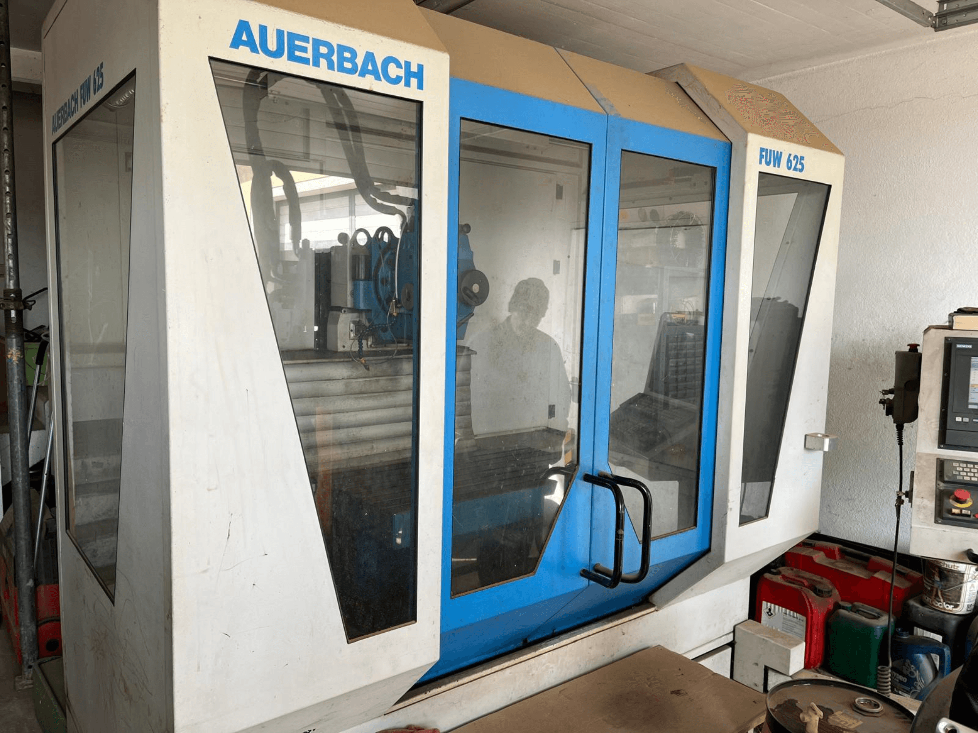 Centro de mecanizado universal FUW 625 de Auerbach en vista lateral, con paneles de cristal y un panel de control a la derecha.