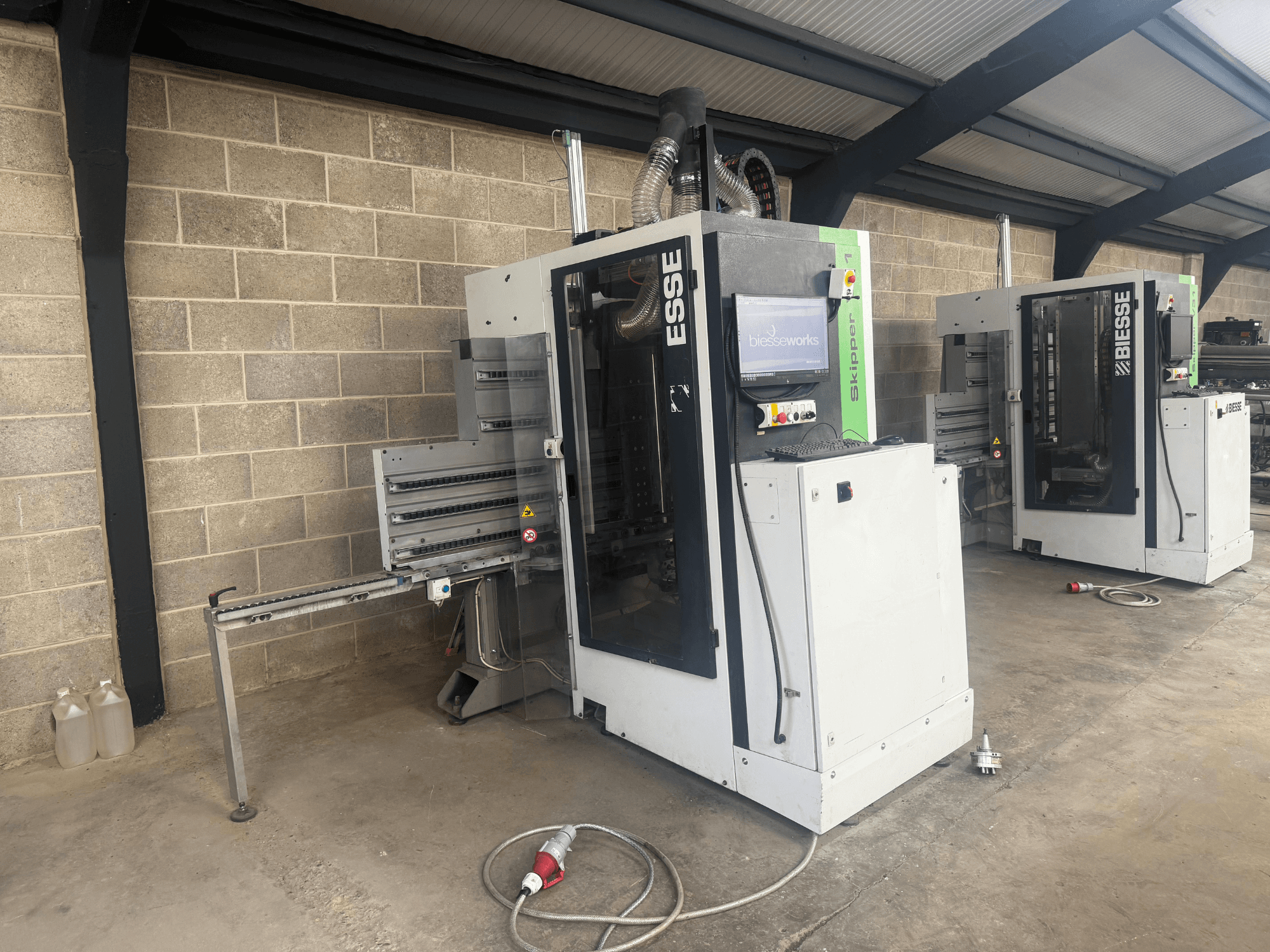 Taladradora de madera BIESSE Skipper v31 en vista lateral, con panel de control y maquinaria adyacente, situada en un taller.