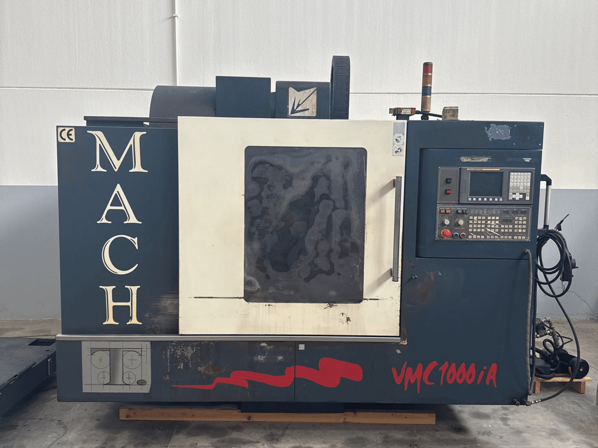 Centro de mecanizado vertical MIND MACH VMC 1000/A en vista frontal, con panel de control, husillo y marcas en la base.