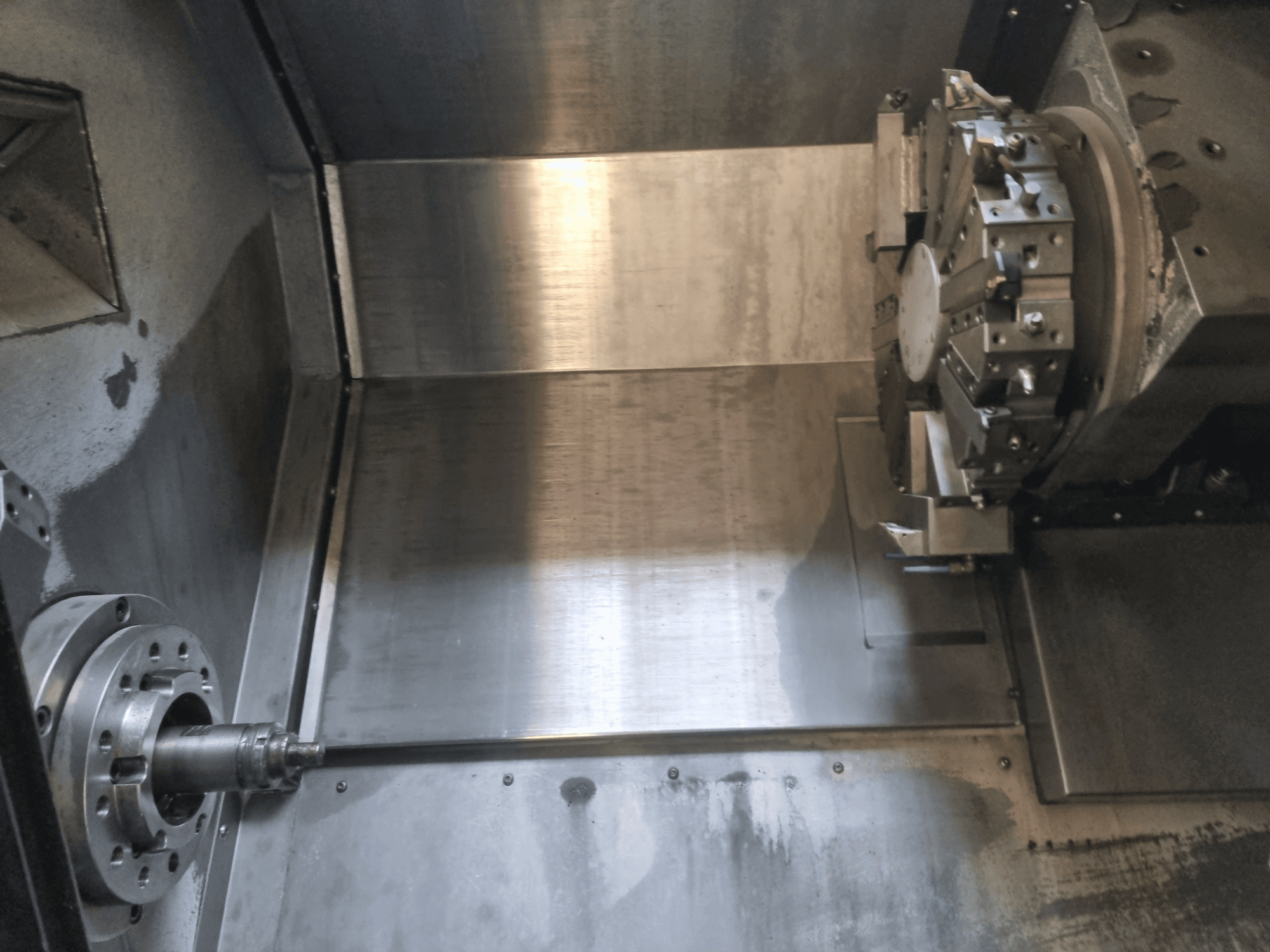 Vista interior de un torno CNC, con husillo giratorio y superficie de trabajo metálica, que muestra la ingeniería de precisión industrial.