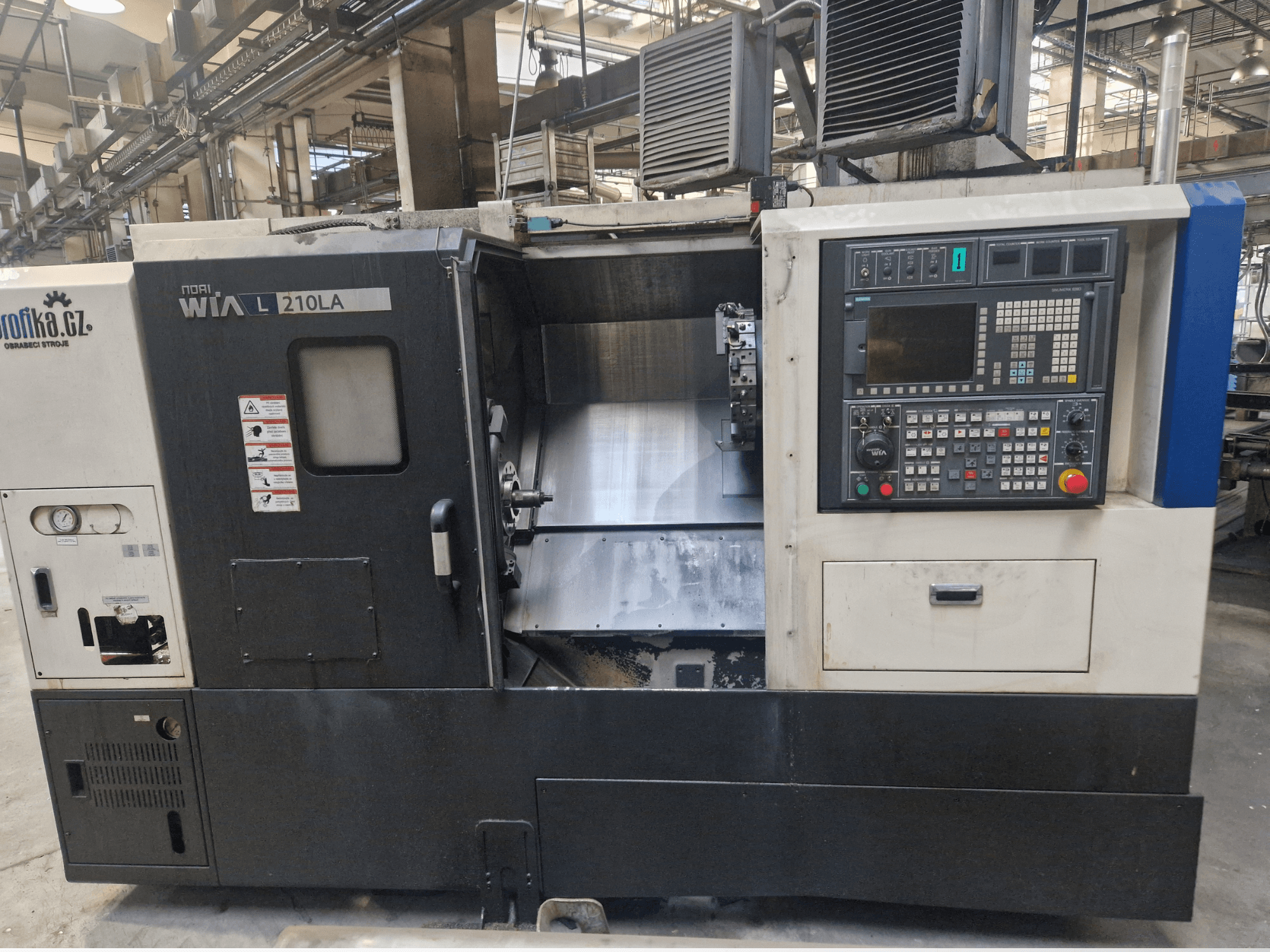 Máquina de torno CNC WIA L210LA, vista frontal, presenta panel de control con botones, pantalla y un área de mecanizado visible.