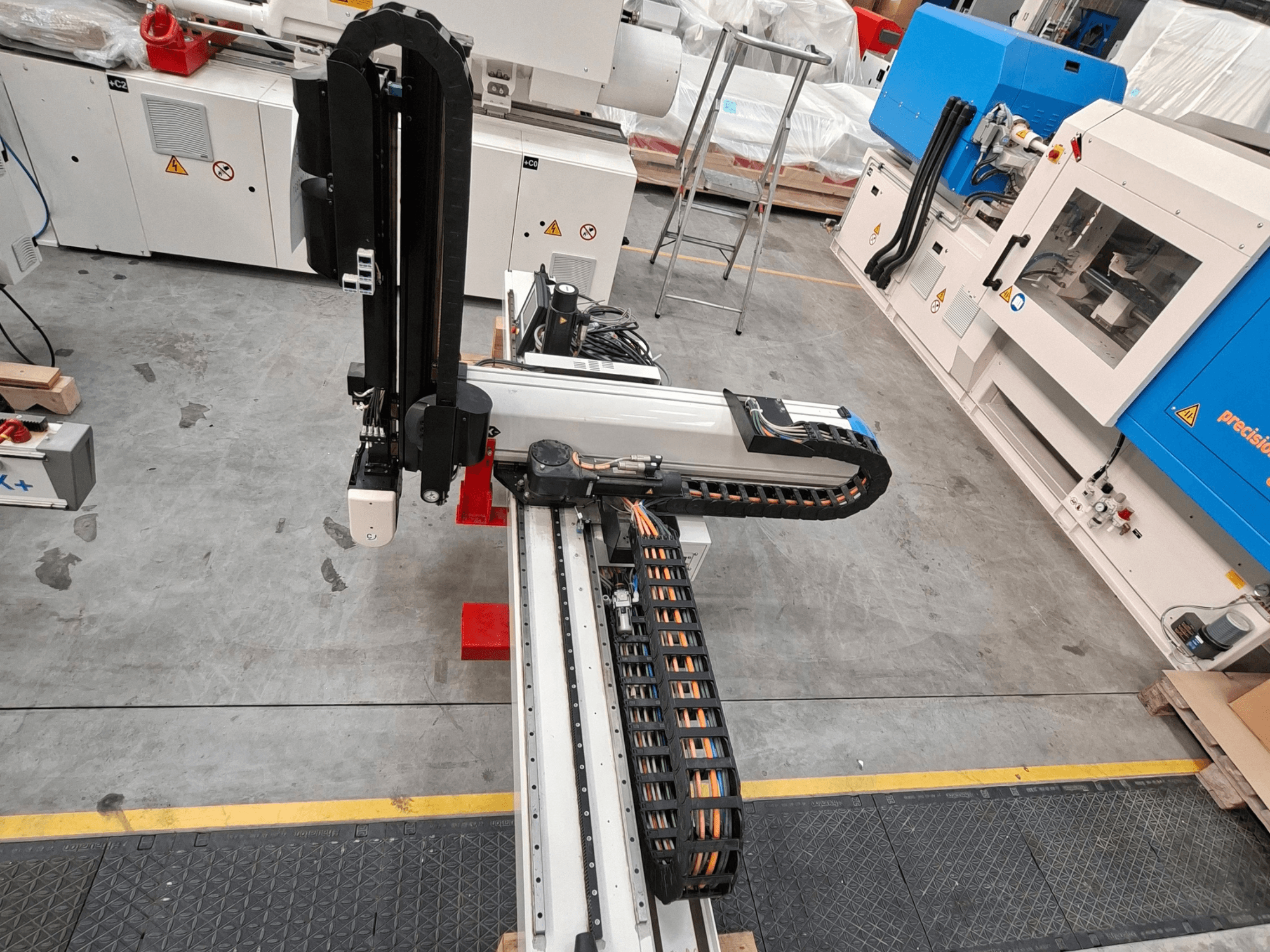 Máquina de procesamiento de plástico Krauss Maffei LRX150-MC5 vista desde arriba, en la que se aprecian el brazo robótico y el canal para cables en la planta de producción.