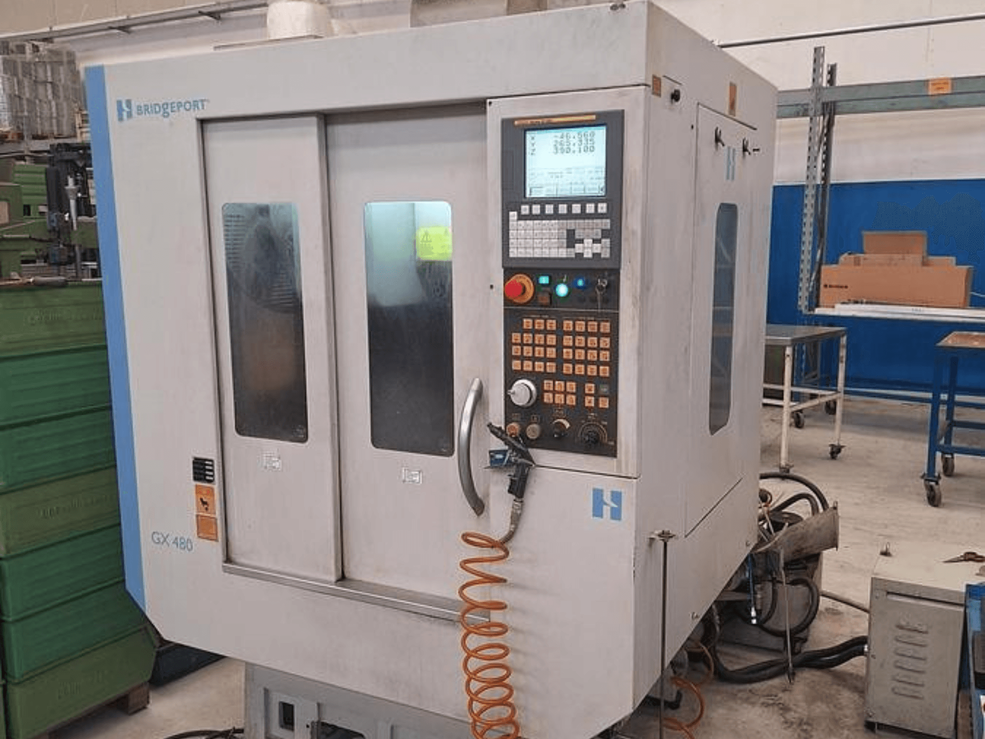 Centro de mecanizado vertical Bridgeport GX 480 en vista frontal, con panel de control, puertas dobles de cristal y manguera flexible.