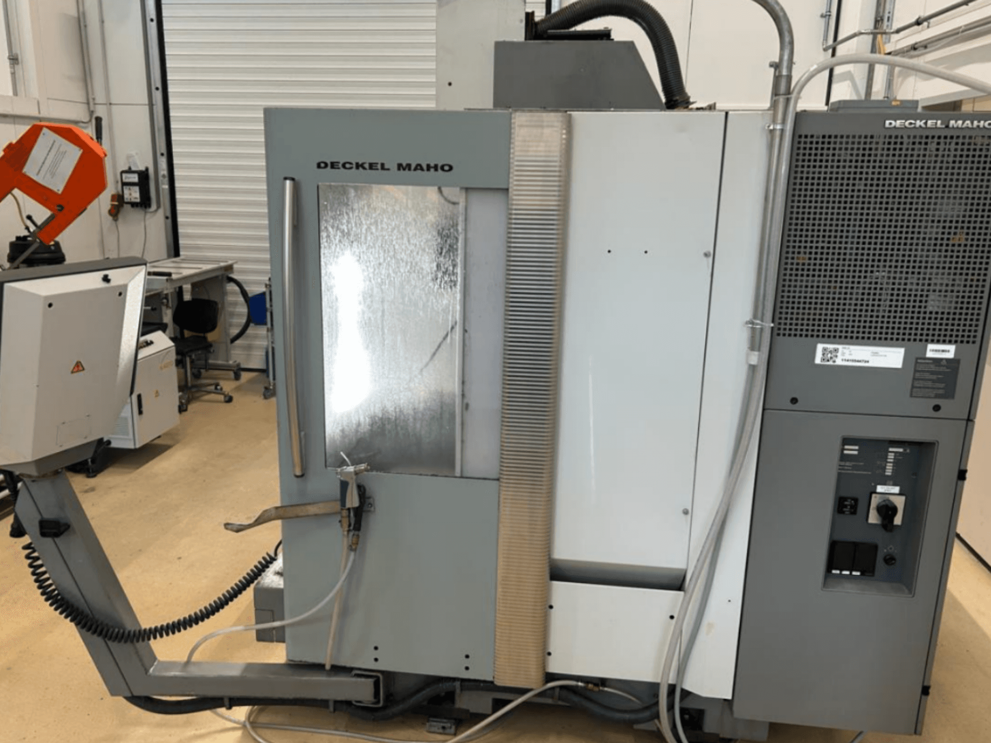 Vista frontal del centro de mecanizado vertical DECKEL MAHO DMU 50, en la que se aprecian los mandos, el sistema de refrigeración y la zona de mecanizado con panel reflectante.