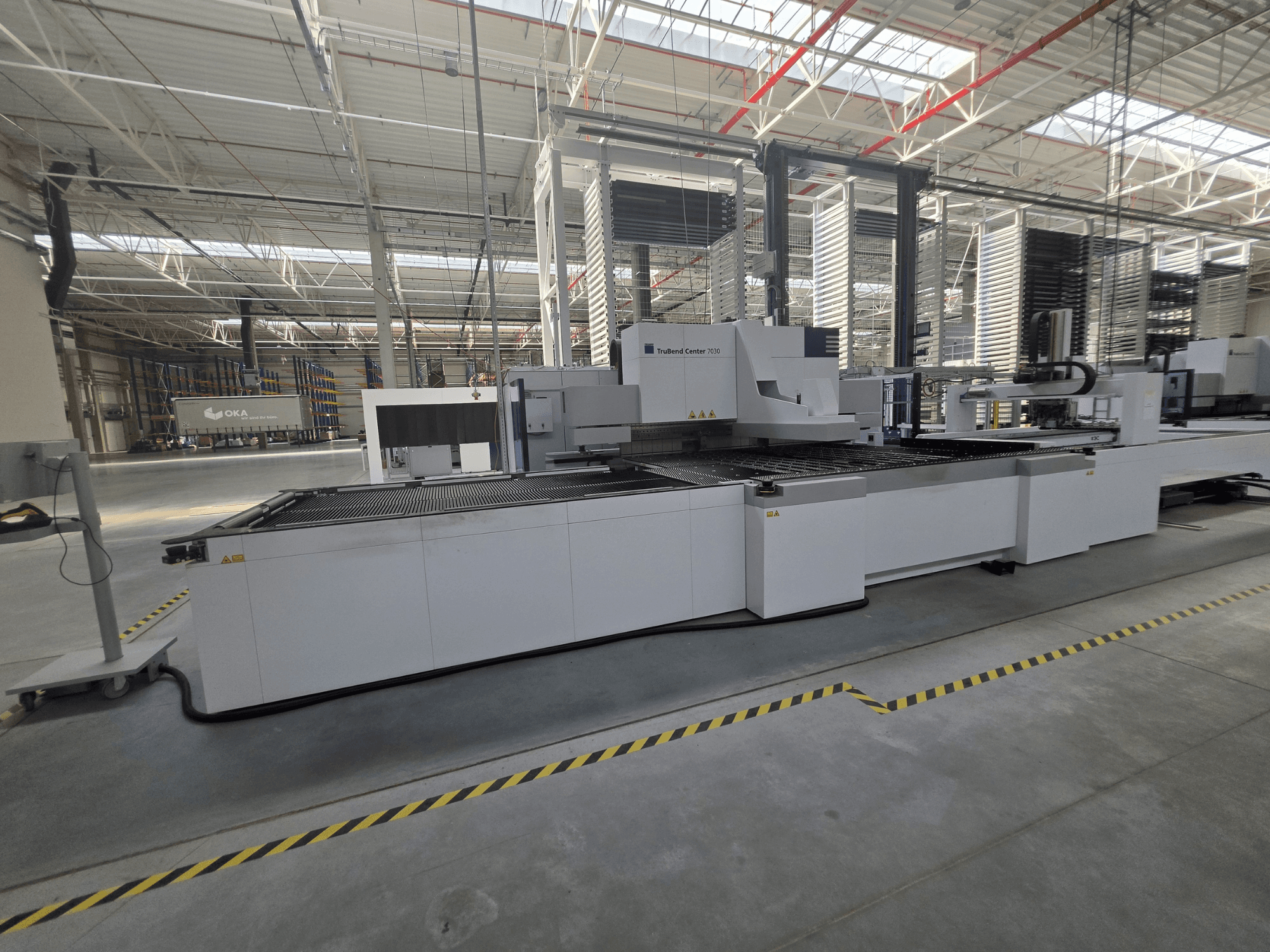 Plegadora TRUMPF TruBend Center 7030, vista lateral, en la que se aprecian la zona de trabajo y los mandos en un amplio taller.