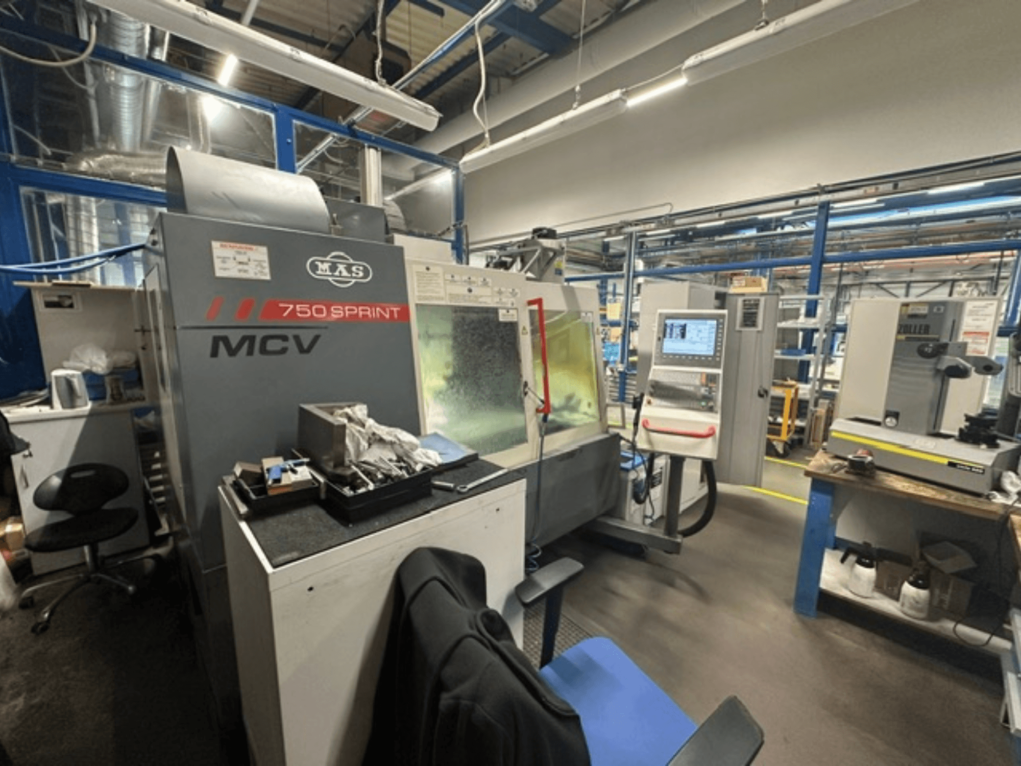 Centro de mecanizado vertical KOVOSVIT MAS MCV 750 Sprint en un taller, en el que se aprecian el panel de control y la zona de trabajo desde una vista lateral.