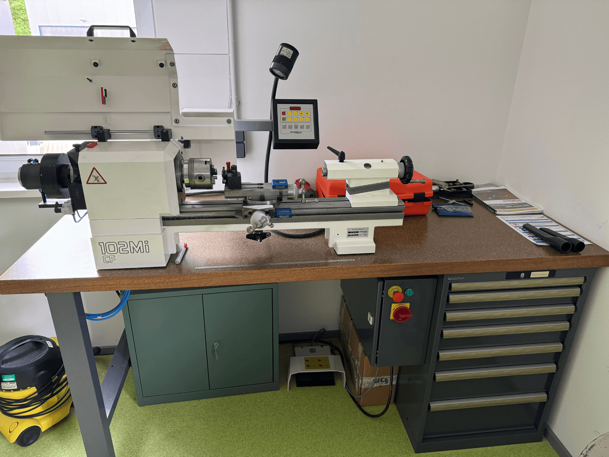 Torno horizontal SCHAUBLIN 102Mi W25 en un taller, vista frontal con detalles del panel de control y del banco de trabajo.