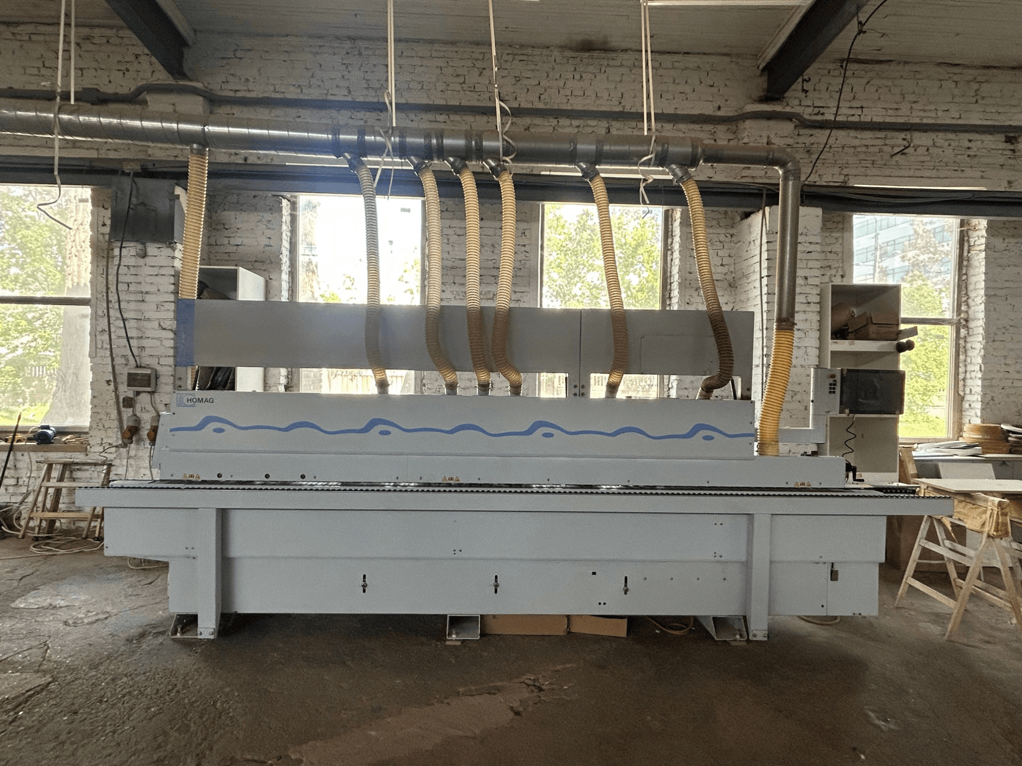 Vista frontal de la chapadora de cantos HOMAG Optimat KDF 440 C, en la que se aprecia una máquina de gran tamaño con mangueras de aspiración de polvo y un panel de control.