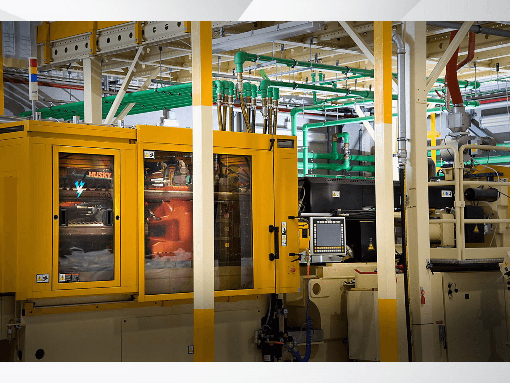 Máquina industrial Husky en amarillo, vista frontal que muestra el panel de control y los mecanismos internos sobre un fondo de fábrica.