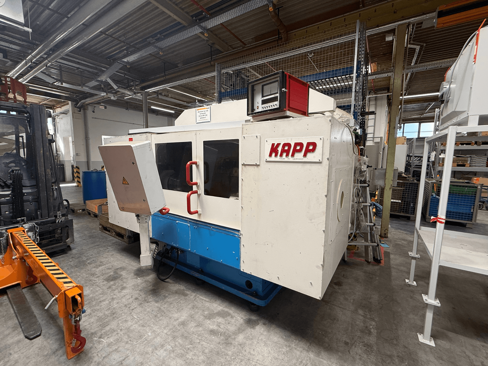Rectificadora cilíndrica KAPP RNS 55 vista de perfil, con el panel de control y la cabina de seguridad, en un entorno de taller.