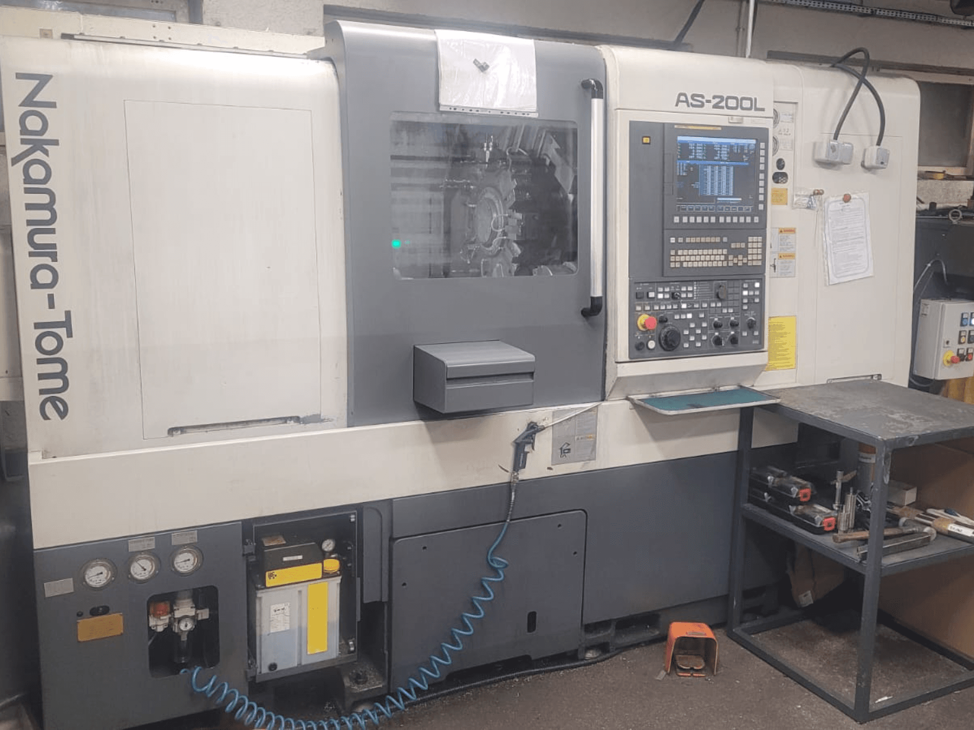 Máquina de torneado horizontal NAKAMURA-TOME AS-200L, vista frontal que muestra el panel de control, el husillo y las características de la máquina.