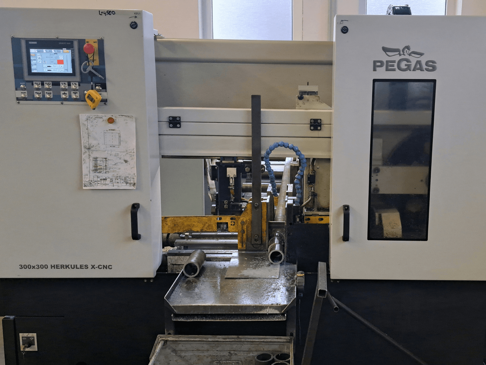 Máquina para chapa Pegas HERKULES X-CNC 300x300, vista frontal, en la que se aprecian el panel de control y la zona de trabajo con piezas metálicas.