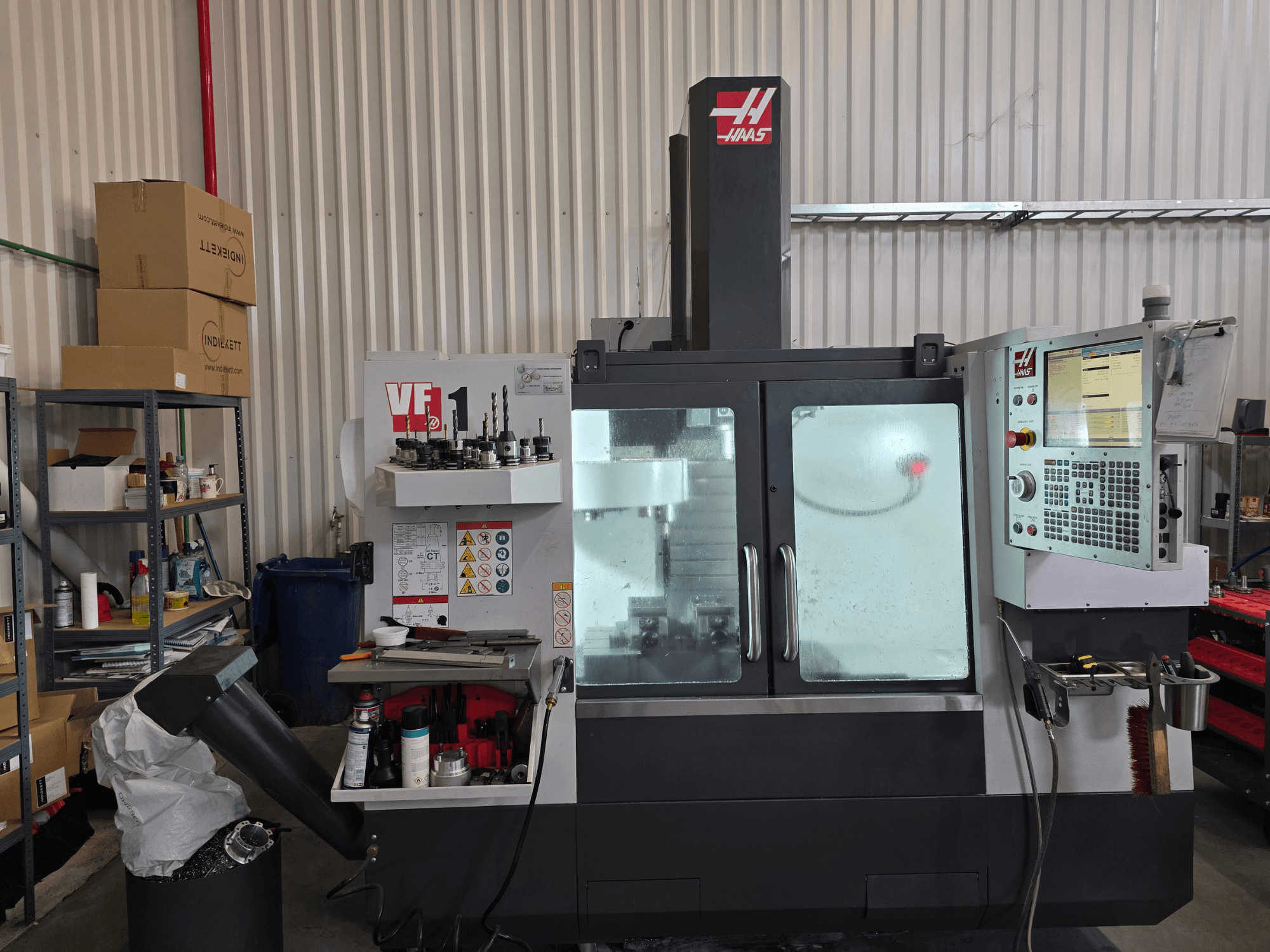 Centro de mecanizado vertical HAAS VF 1 en un taller, vista frontal mostrando el panel de control y la zona de fresado con herramientas.
