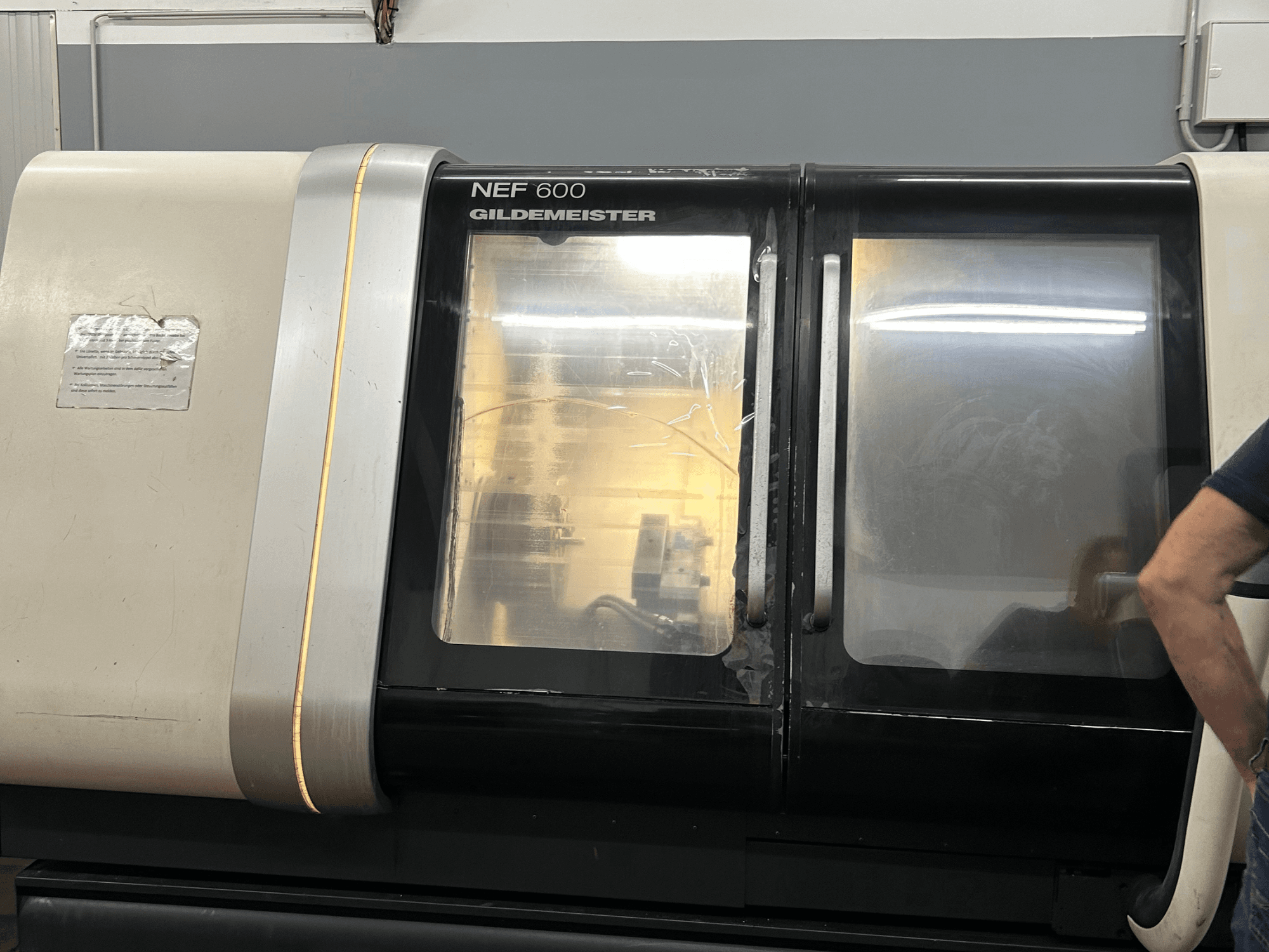 Máquina de torneado horizontal DMG NEF 600, vista frontal, con acabado brillante y grandes ventanas de visualización.