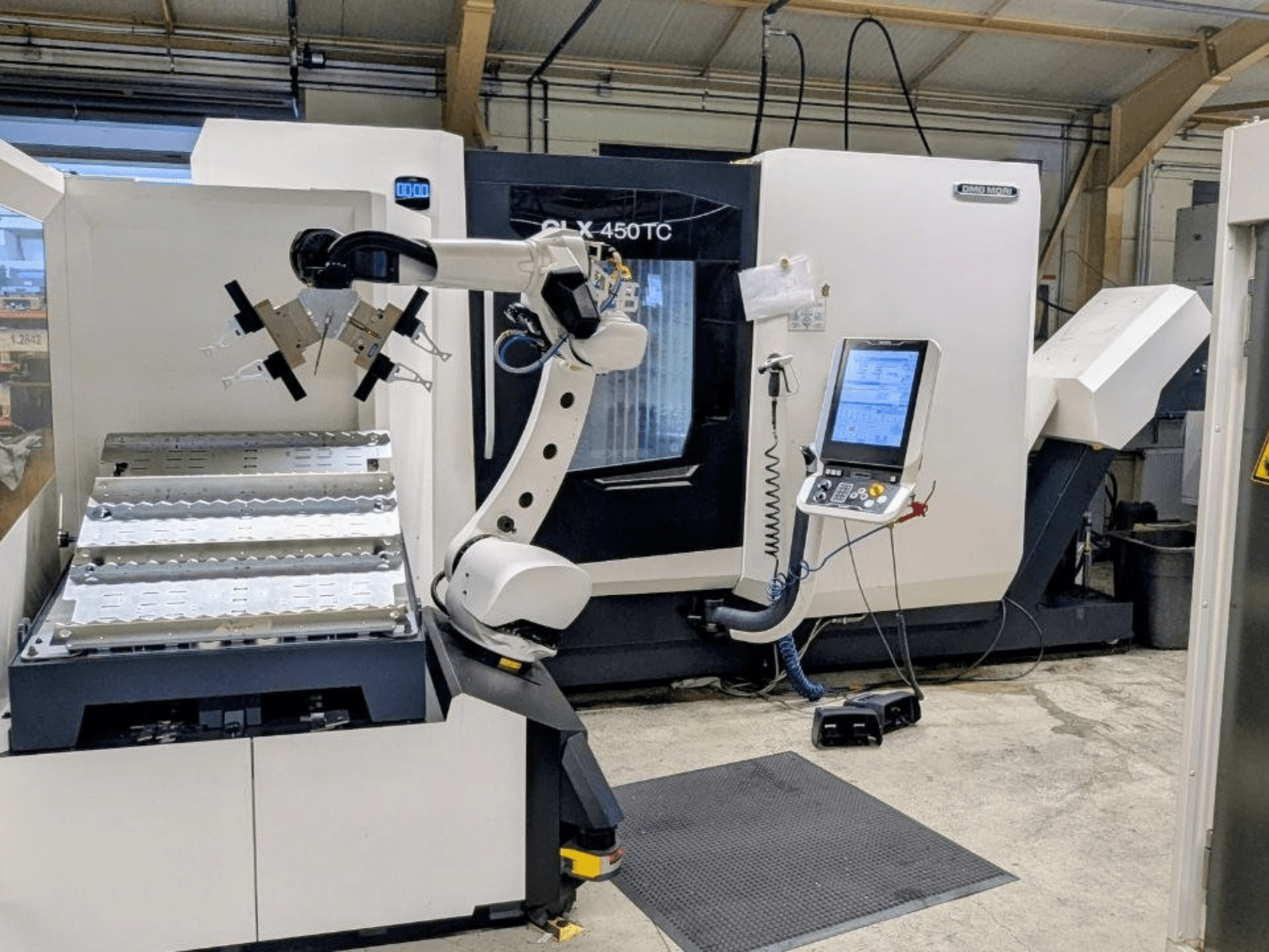 DMG MORI CLX 450 TC con Robo2go, vista frontal, en la que se aprecian el brazo robótico y el panel de control junto a la máquina.