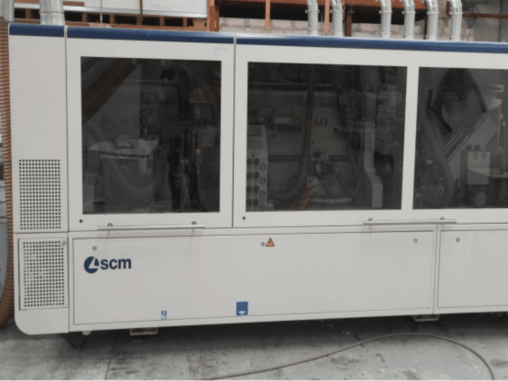 Máquina industrial SCM, vista lateral, cuenta con paneles transparentes y respiraderos visibles; diseñada para la eficiencia en los procesos de fabricación.