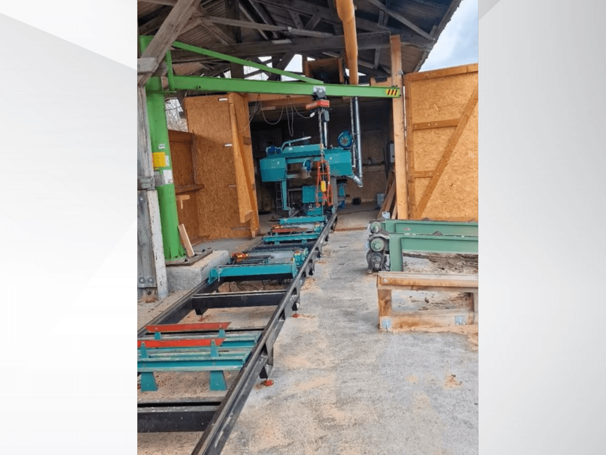 Sierra de cinta horizontal en taller, vista de frente. El equipo incluye una pista y accesorios verdes adicionales.