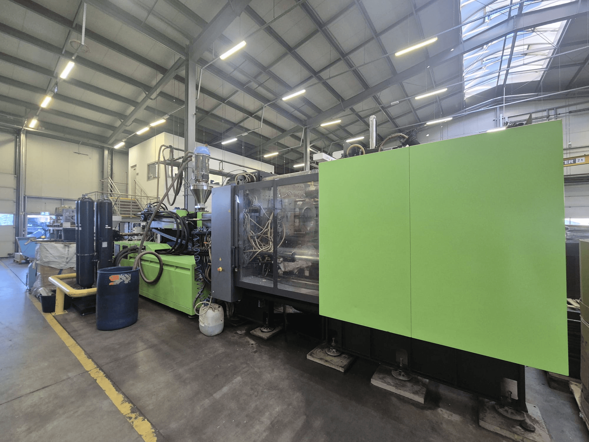Máquina de moldeo por inyección hidráulica Engel Duo 5160/700 en un entorno industrial, vista desde un lado, en la que se aprecian su carrocería verde y sus componentes.