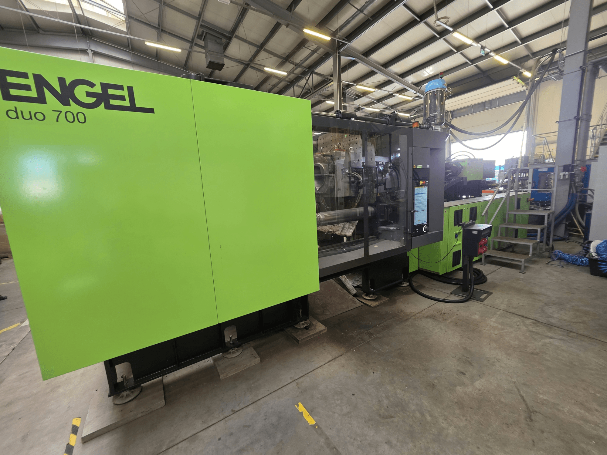 Máquina de moldeo por inyección hidráulica Engel Duo 700, vista frontal, en la que se aprecia el exterior de color verde y el panel de control.