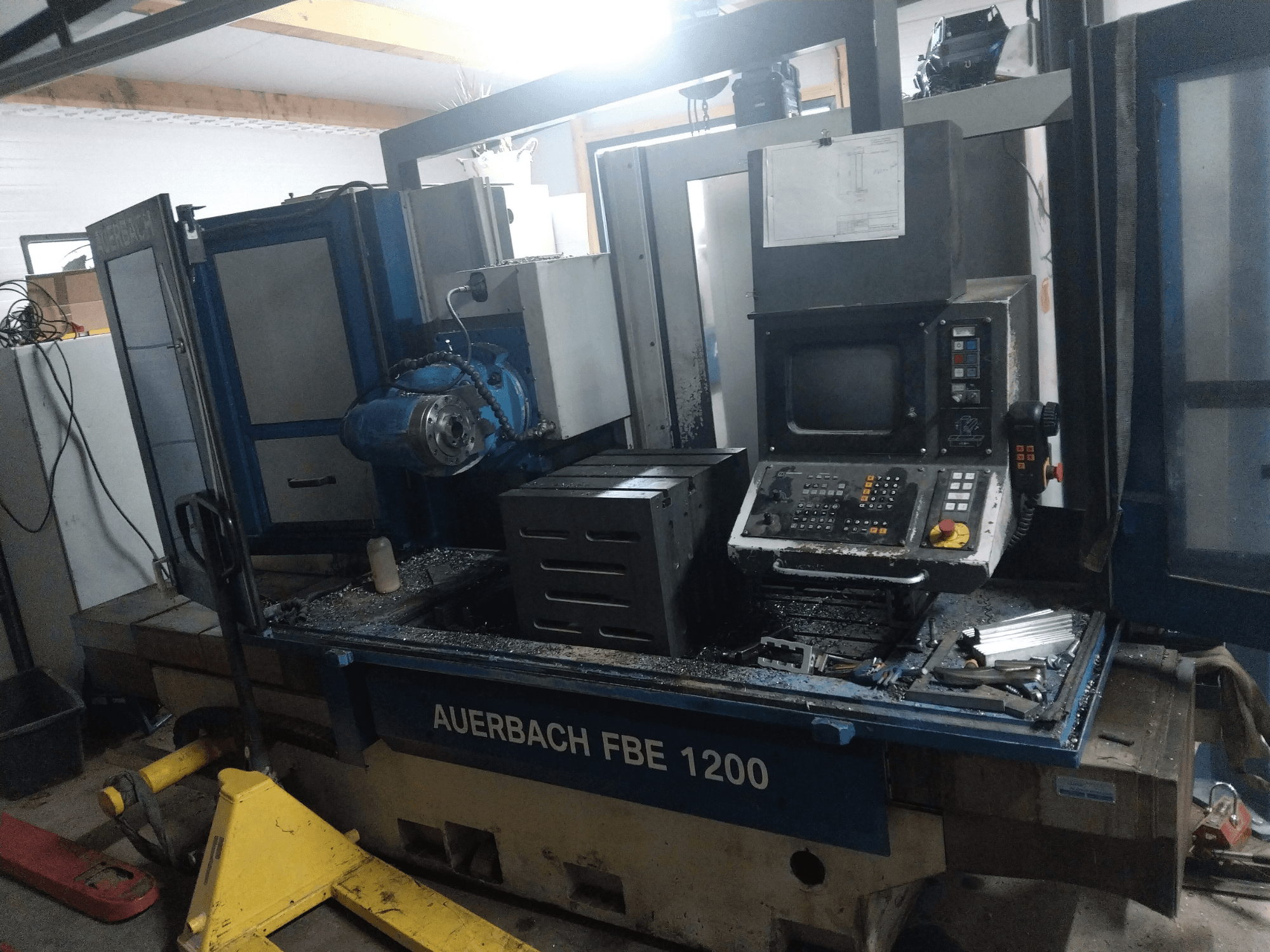 Taladradora de metal Auerbach FBE 1200, vista frontal, mostrando el panel de control, el motor y virutas de metal en la superficie de trabajo.