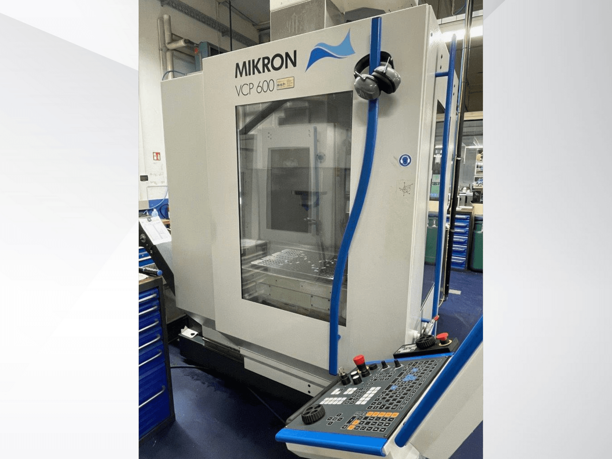 Centro de mecanizado Mikron VCP 600 en un taller, vista frontal, con un panel de control con botones y mandos.
