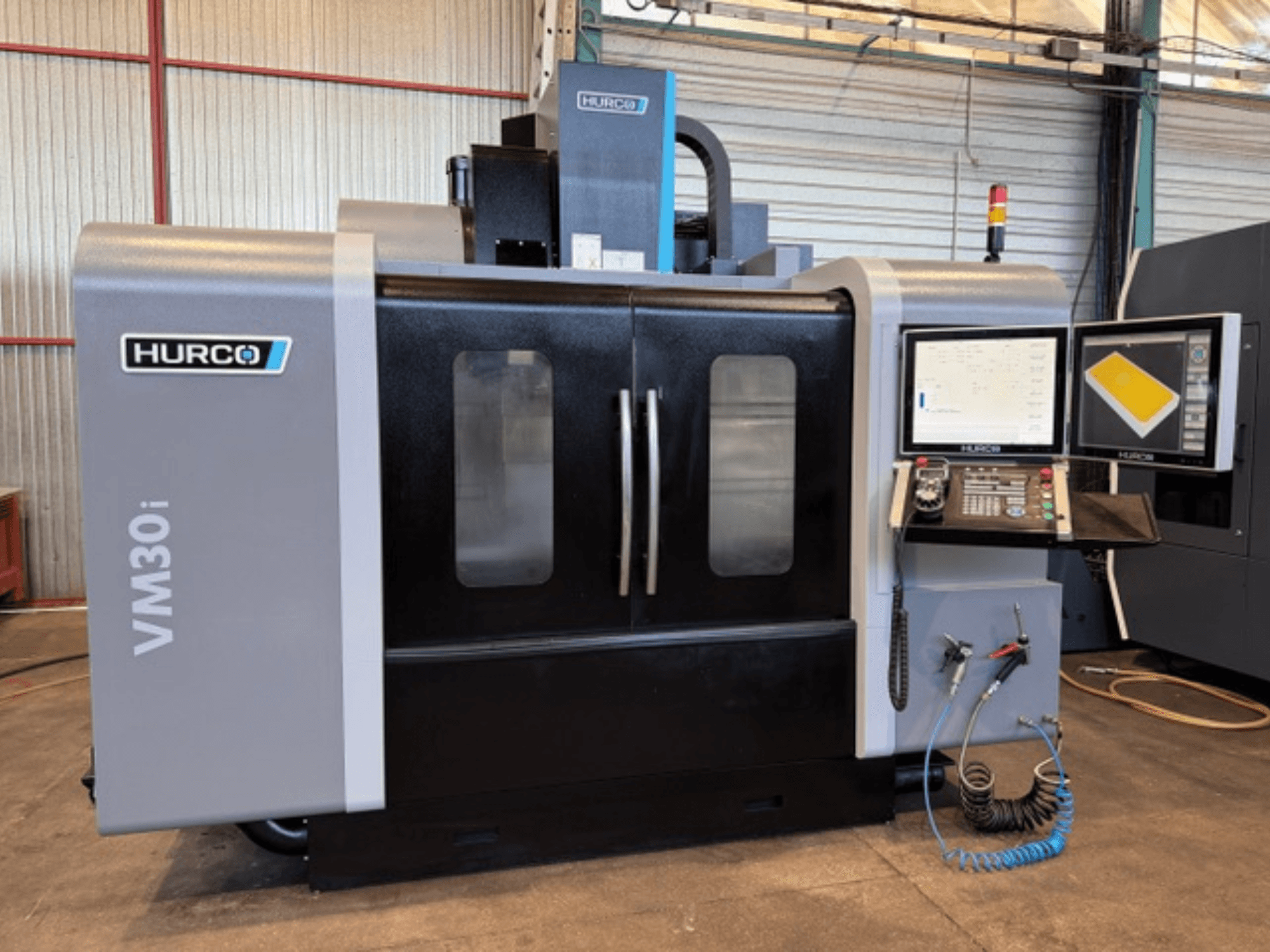 Centro de mecanizado vertical Hurco VM30i, vista frontal que muestra el panel de control, las pantallas de visualización y las puertas de la máquina.
