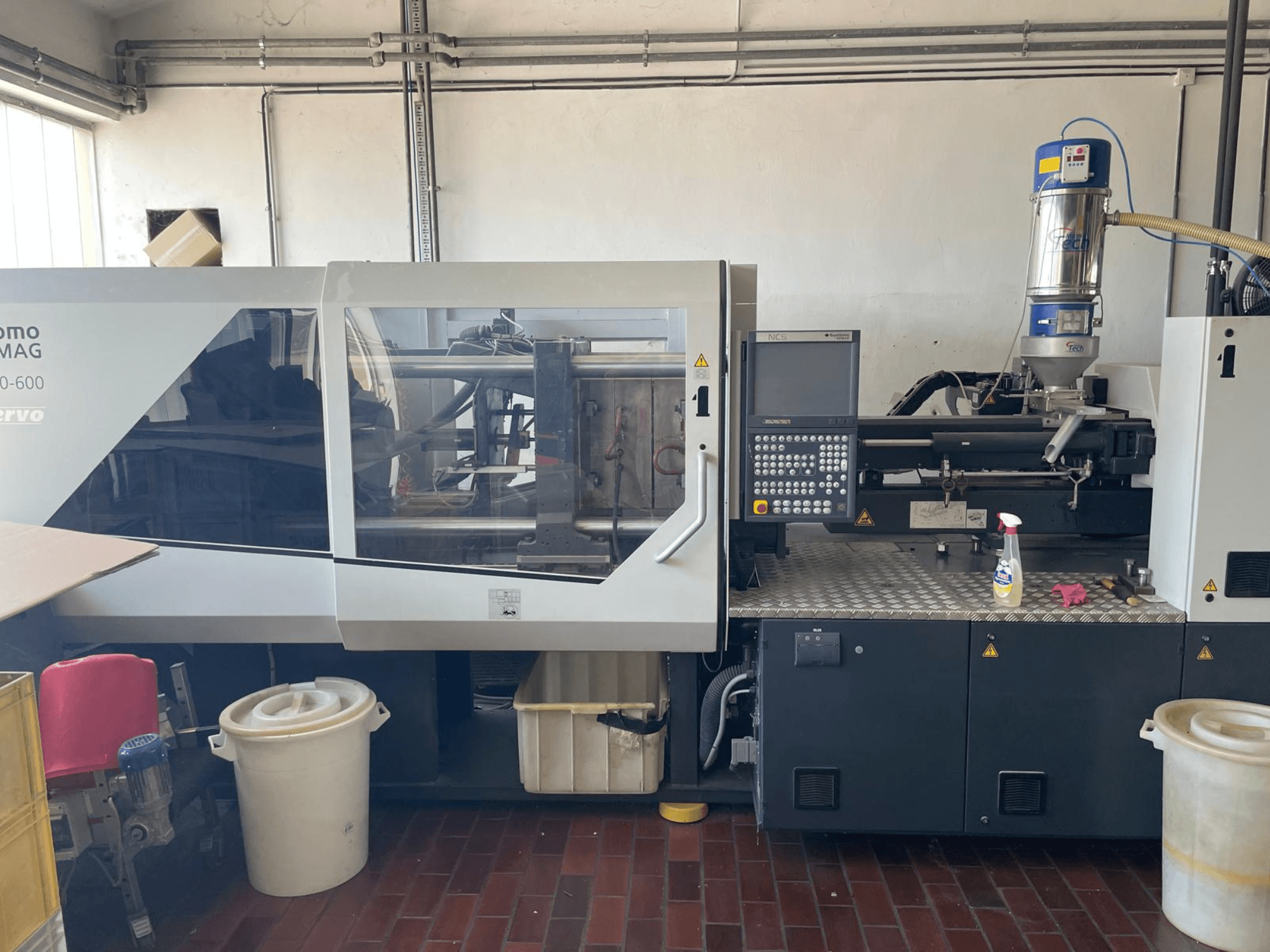 Vista frontal de la máquina de moldeo por inyección hidráulica SUMITOMO SHI DEMAG Systec 160/520-600 con panel de control y unidad de alimentación.