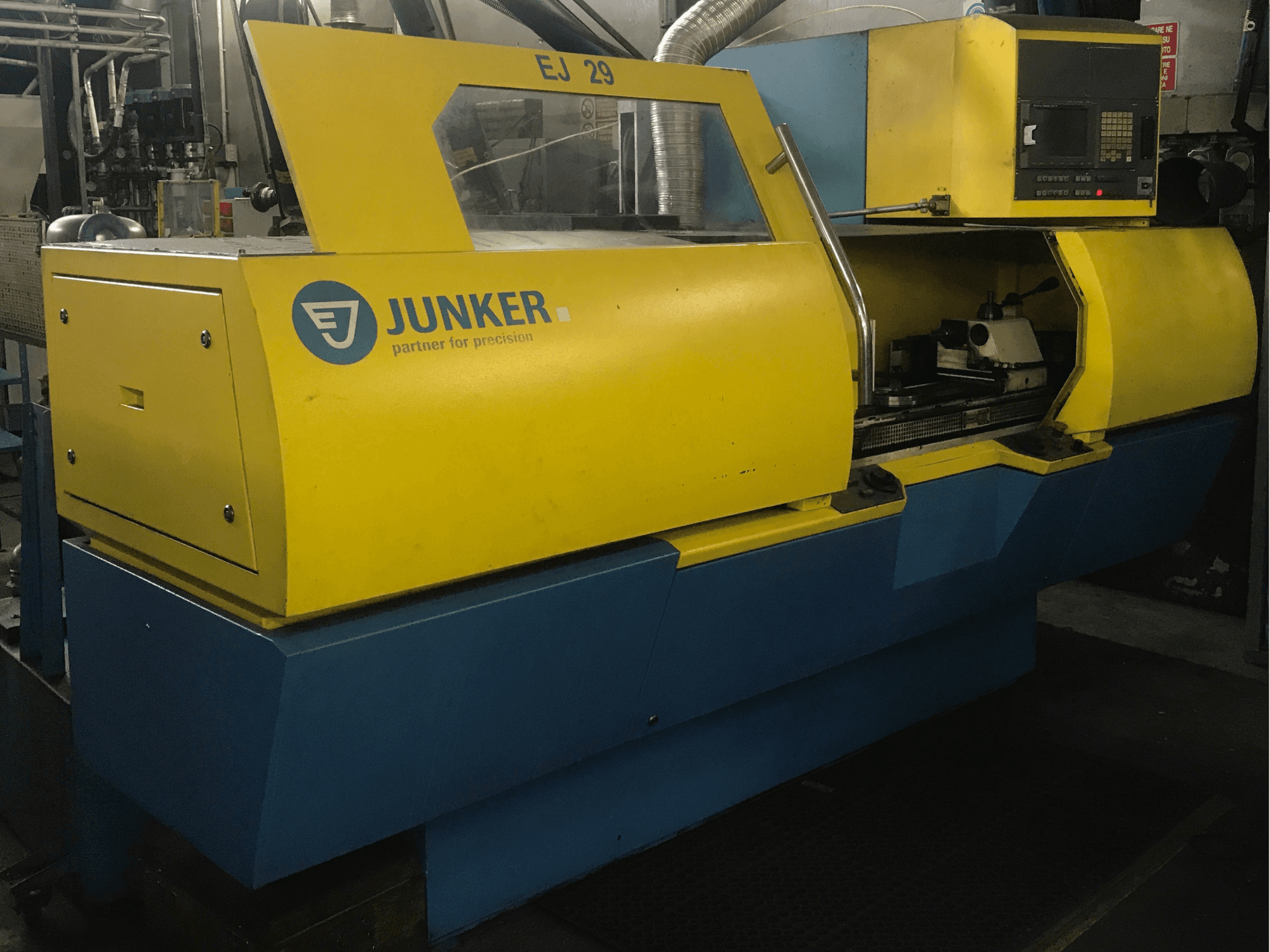 Rectificadora JUNKER EJ 29, vista frontal, presenta carcasa amarilla y azul, panel de control y componentes internos visibles.
