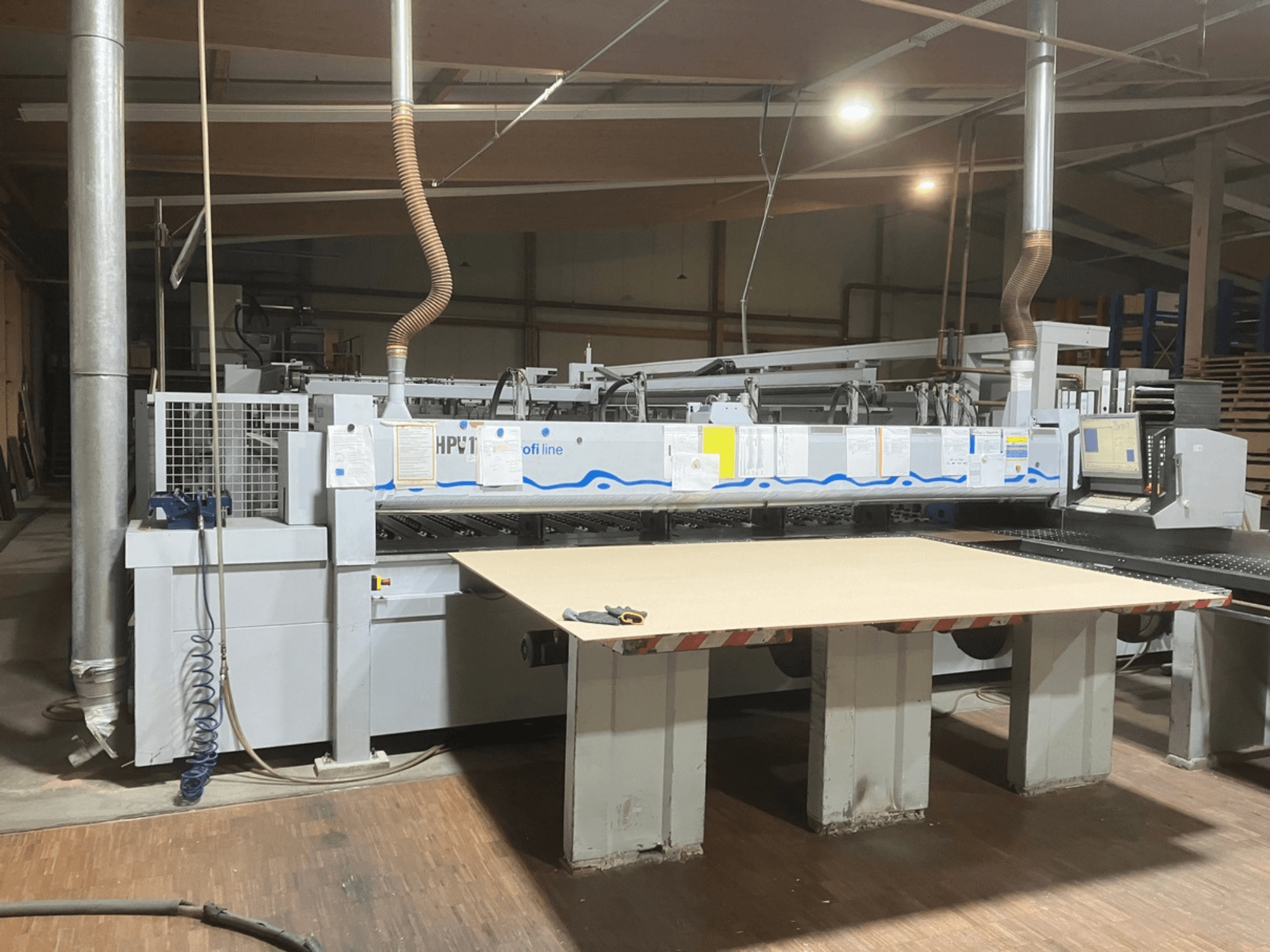 Sierra de paneles HOLZMA HPV11 en un taller, vista frontal en la que se aprecia una superficie de trabajo amplia y plana, así como el panel de control.