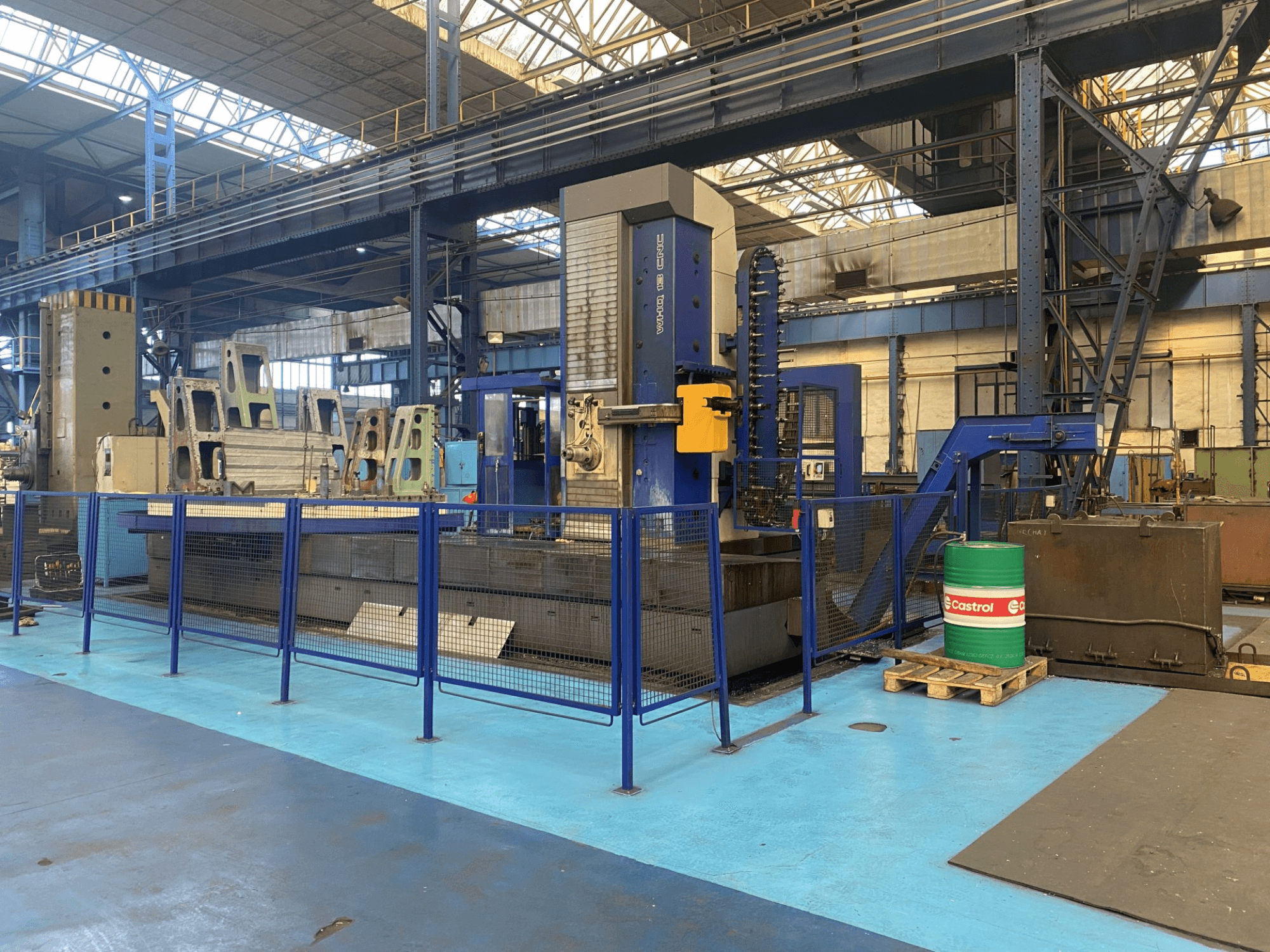 Mandrinadora CNC TOS WHQ 13 en un taller, vista frontal, mostrando el bastidor azul y la valla de seguridad circundante.