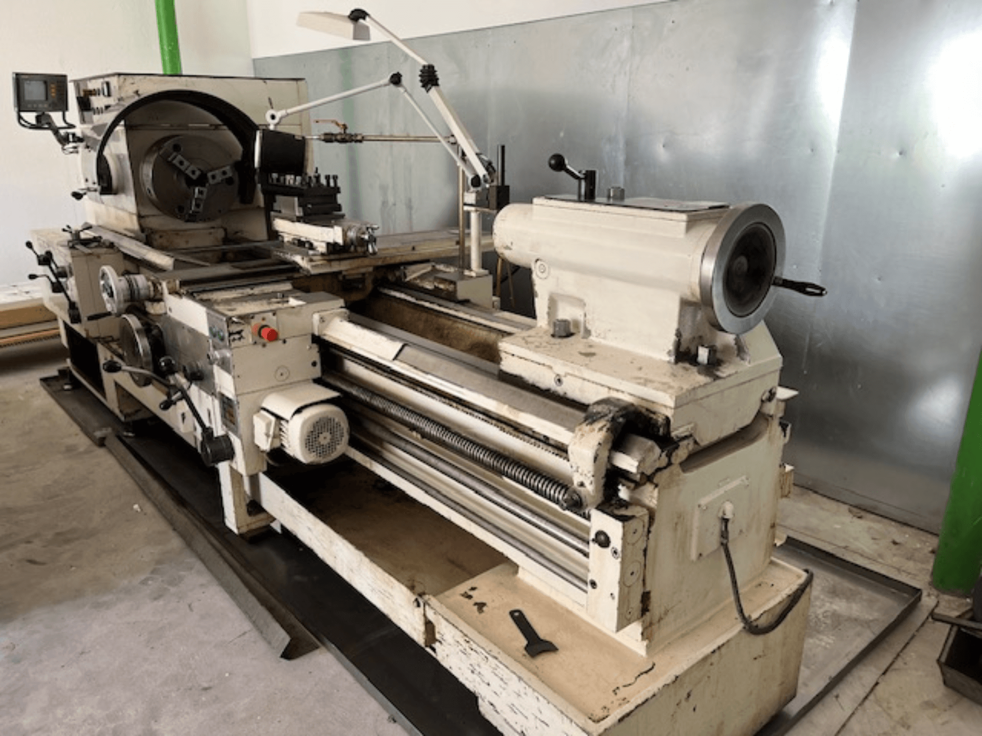 Máquina de torno de metal de época con panel de control y herramientas, vista lateral, mostrando los elementos operativos y el acabado del metal.