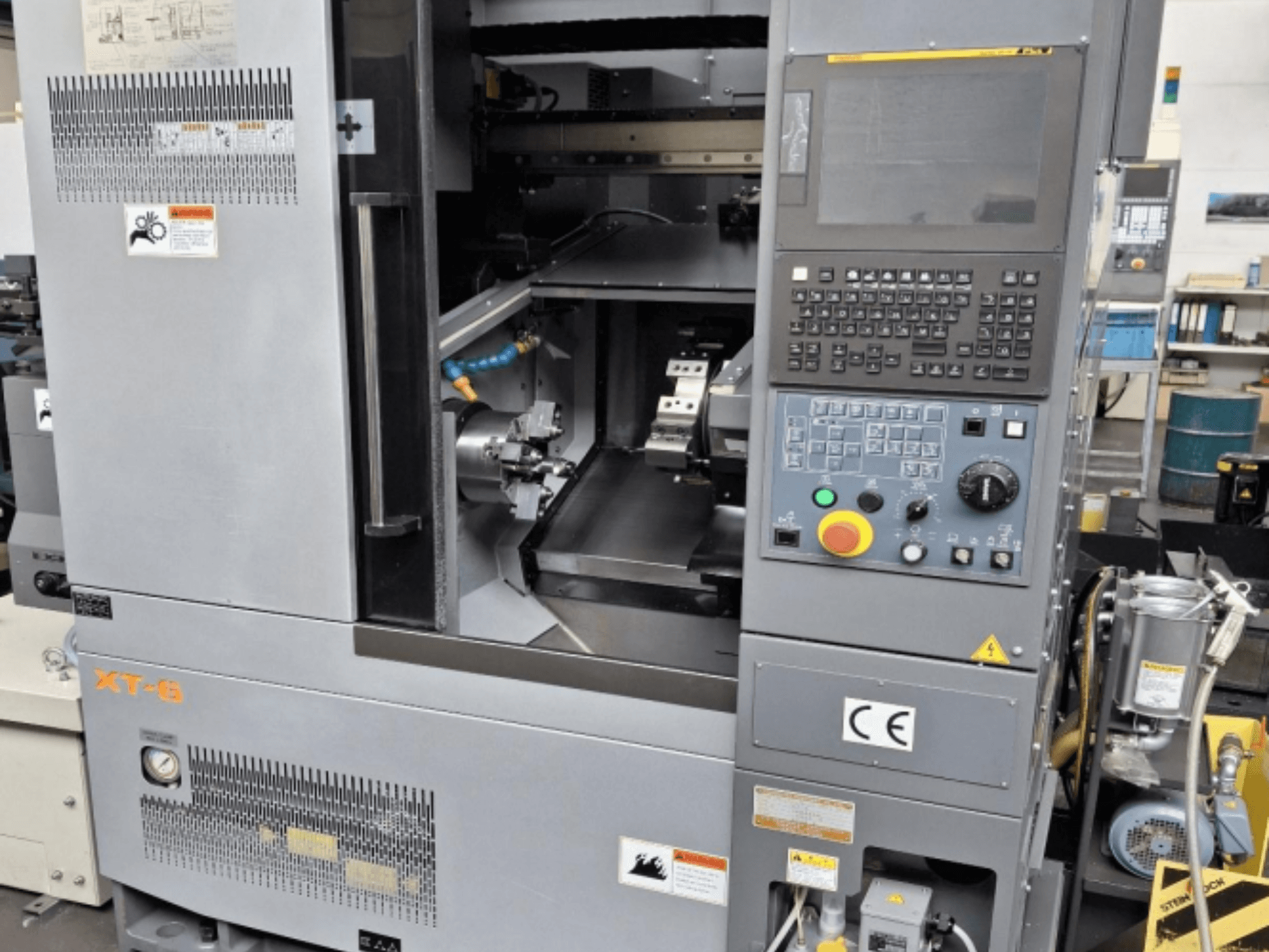 Máquina de torneado horizontal Takamaz XT 6, vista frontal que muestra el panel de control, el área de mecanizado y los detalles de las etiquetas.