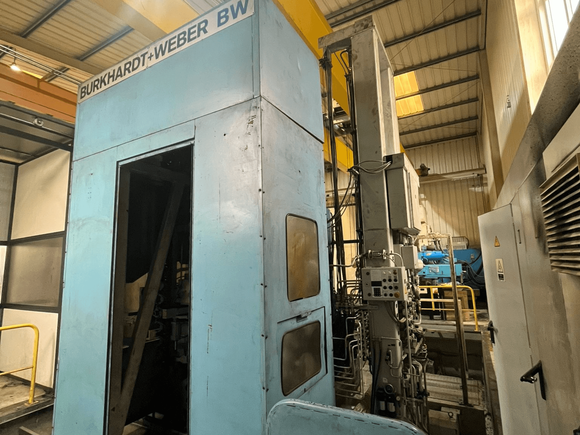 Centro de mecanizado horizontal Burkhardt-Weber MC100, vista lateral en la que se aprecia el exterior azul y el panel de control con los tubos a la vista.