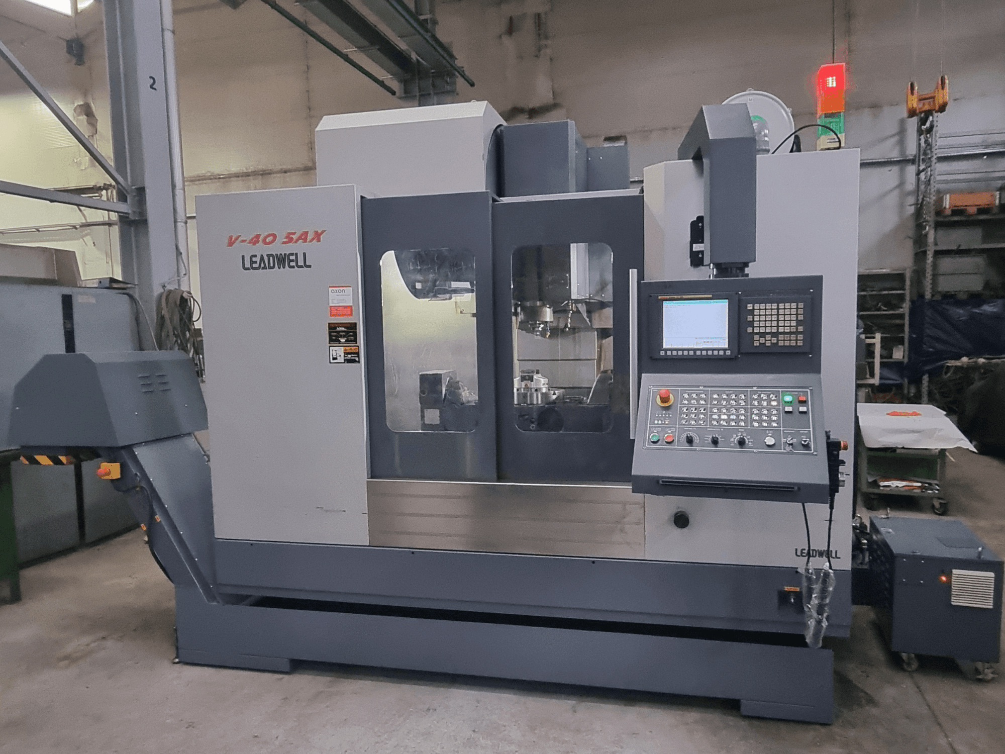 Centro de mecanizado vertical Leadwell V40 5AX, vista frontal, en la que se aprecian el panel de control y la zona de mecanizado con luces de seguridad.