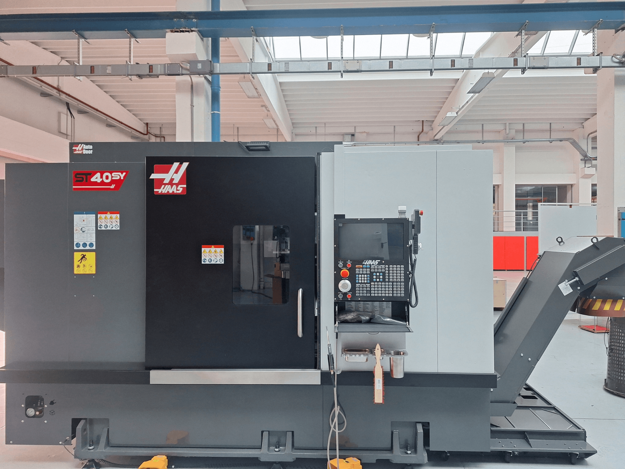 Torno horizontal Haas ST-40SY visto de perfil, en el que se aprecian el panel de control y las etiquetas de seguridad.