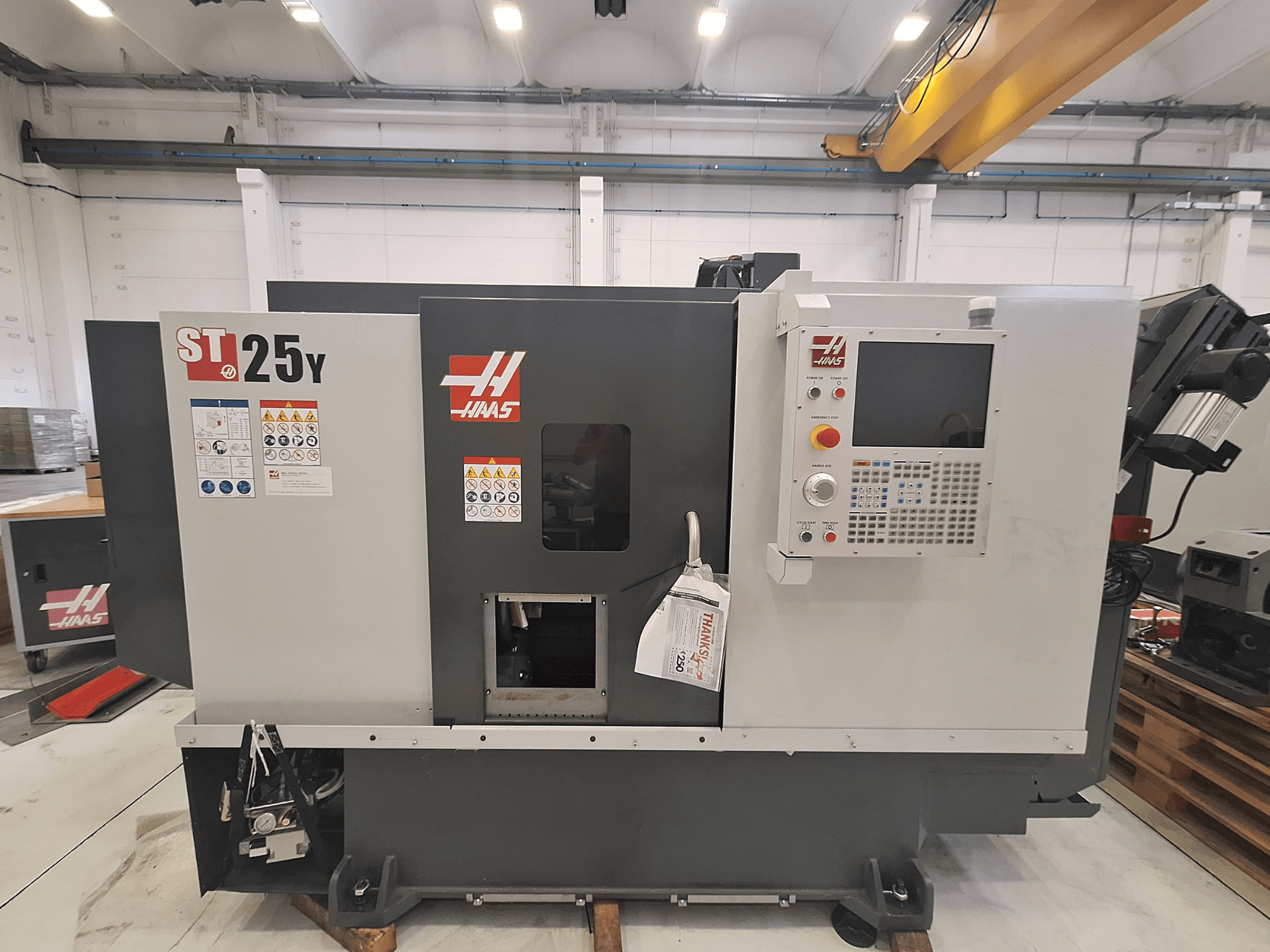 Torno horizontal Haas ST-25Y, vista frontal, con panel de control y etiquetas de seguridad. Ideal para el mecanizado de precisión.