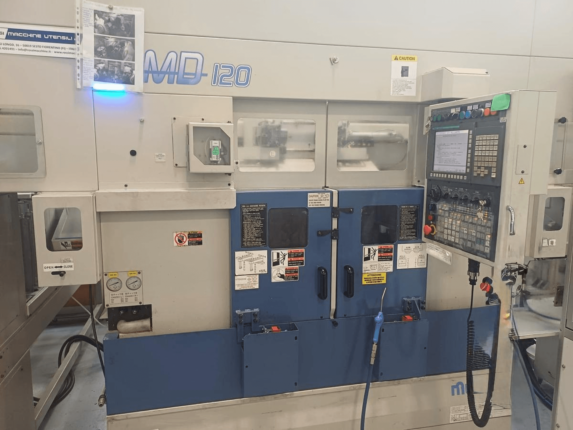 Máquina de torneado horizontal MURATEC MD 120, vista frontal mostrando el panel de control, la puerta y los manómetros.