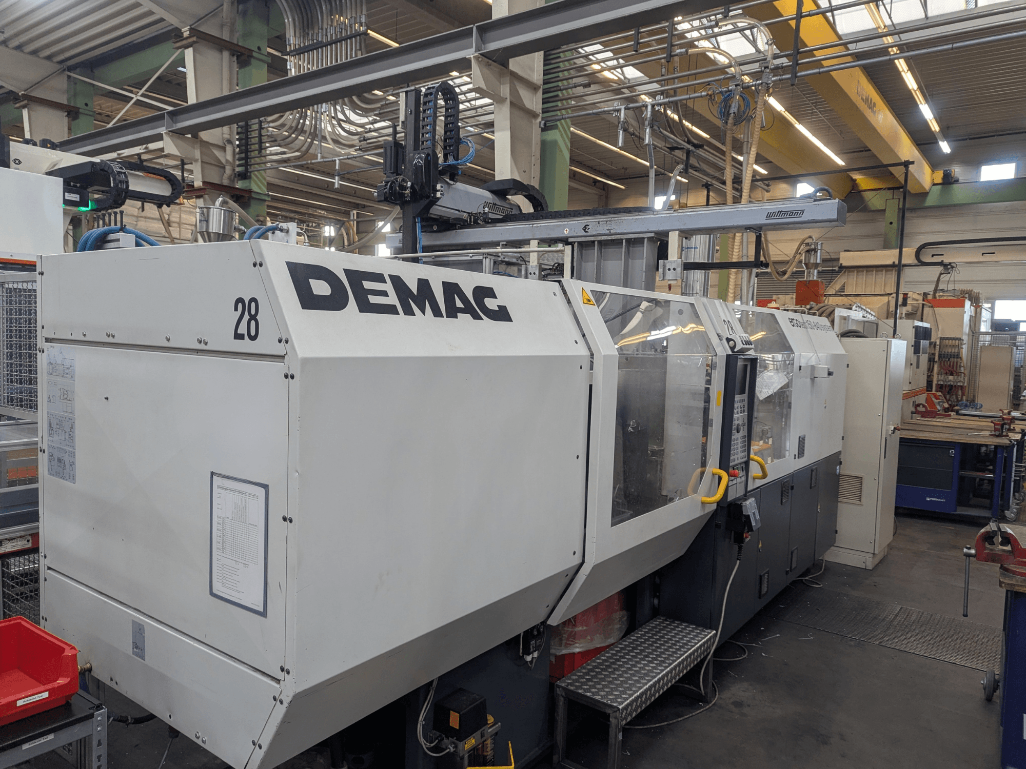 Vista frontal de una máquina de moldeo por inyección hidráulica DEMAG ERGOTECH 1500-840, que muestra los controles operativos y las características de seguridad.