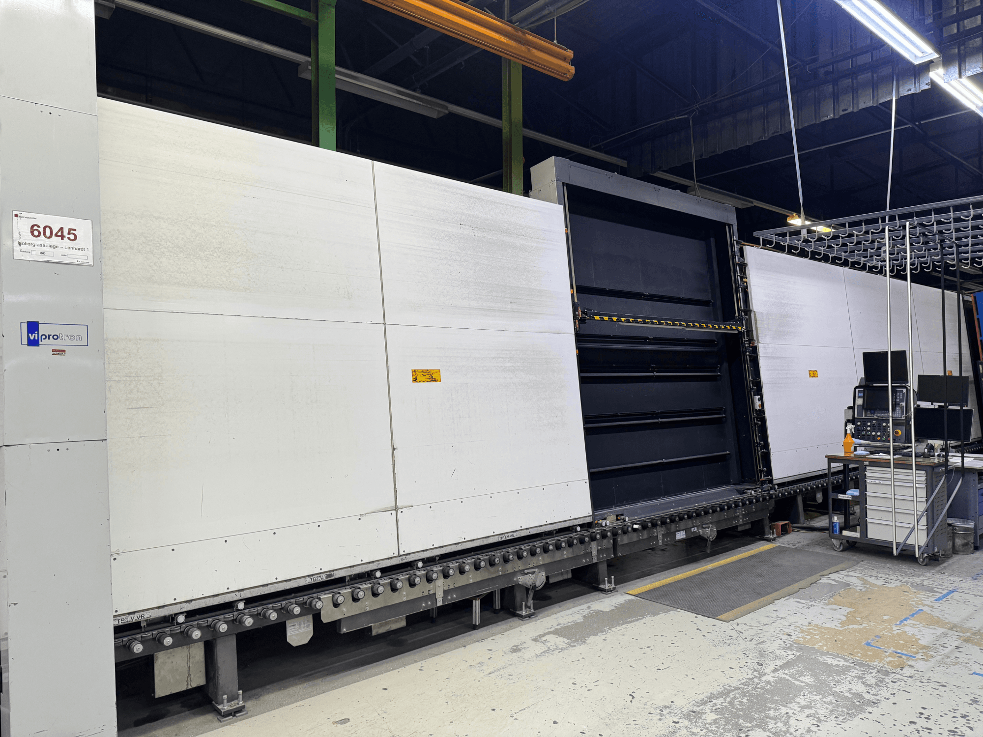 Vista frontal de la máquina de moldeo Vipro con panel abierto, mostrando el equipo operativo y un espacio de trabajo a su lado. Modelo 6045.