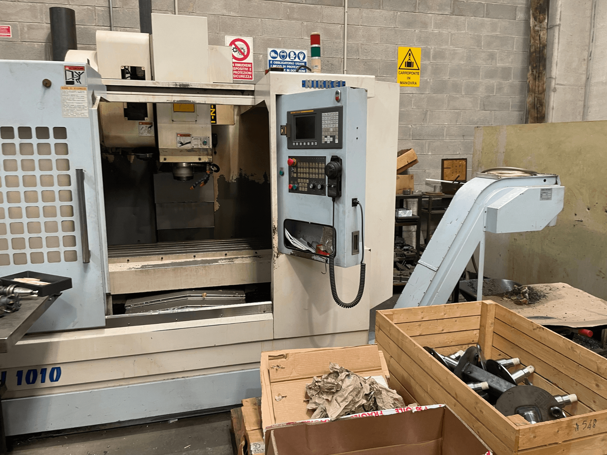 Centro de mecanizado vertical de Other, modelo VH-1010, visto de frente con los mandos visibles y las cajas cerca.