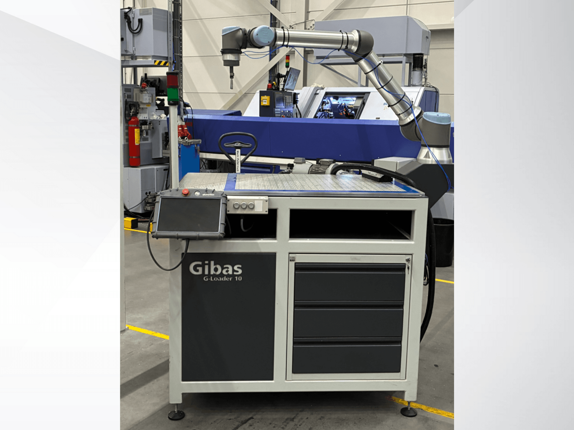 Gibas G-Loader 10 con brazo robótico, vista frontal; dispone de control de pantalla táctil y almacenamiento en cajones en un entorno industrial.