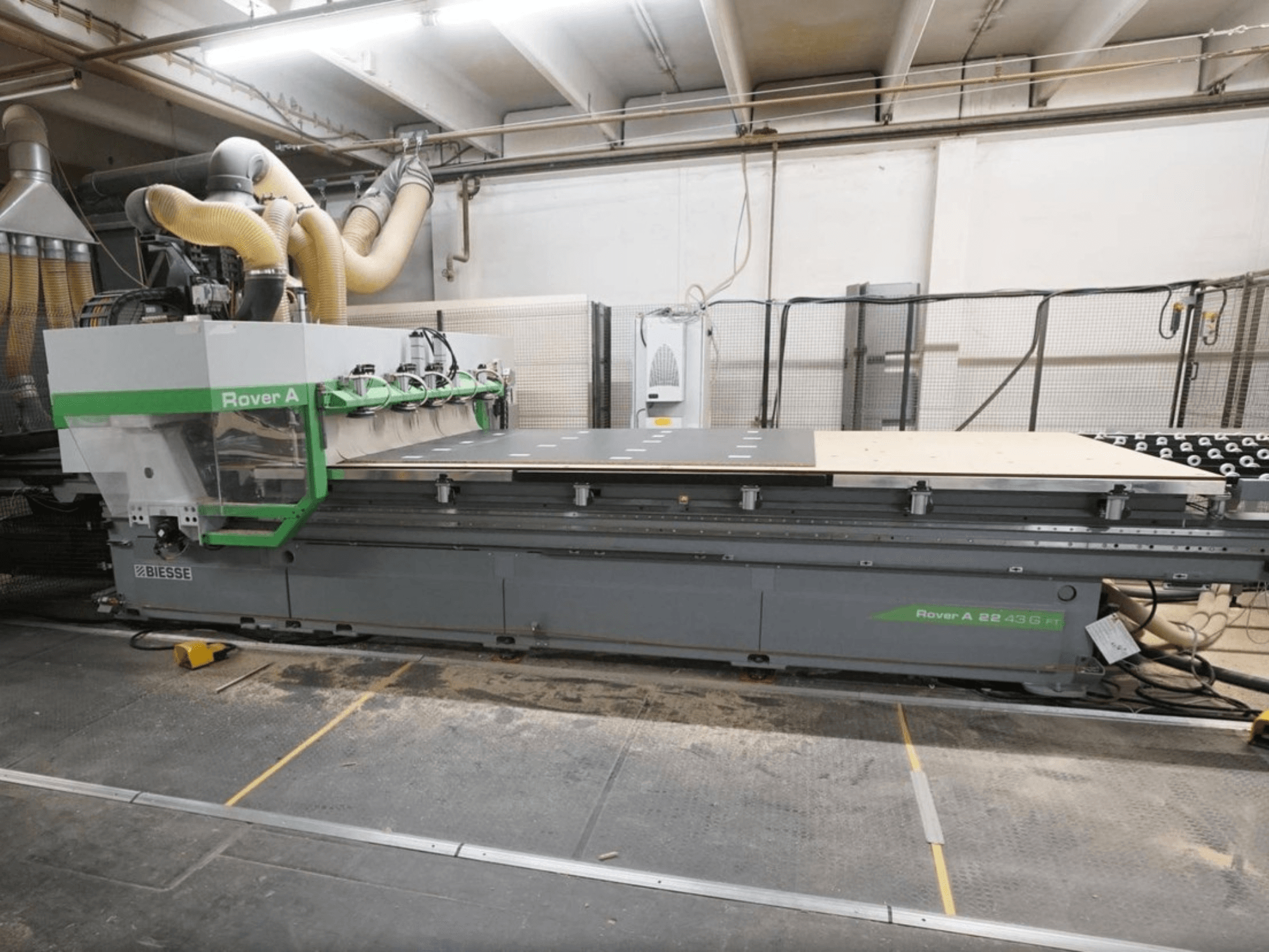 Centro de mecanizado de madera CNC BIESSE Rover A FT 2243, vista frontal, que cuenta con una amplia mesa de trabajo y un sistema de fijación de herramientas.